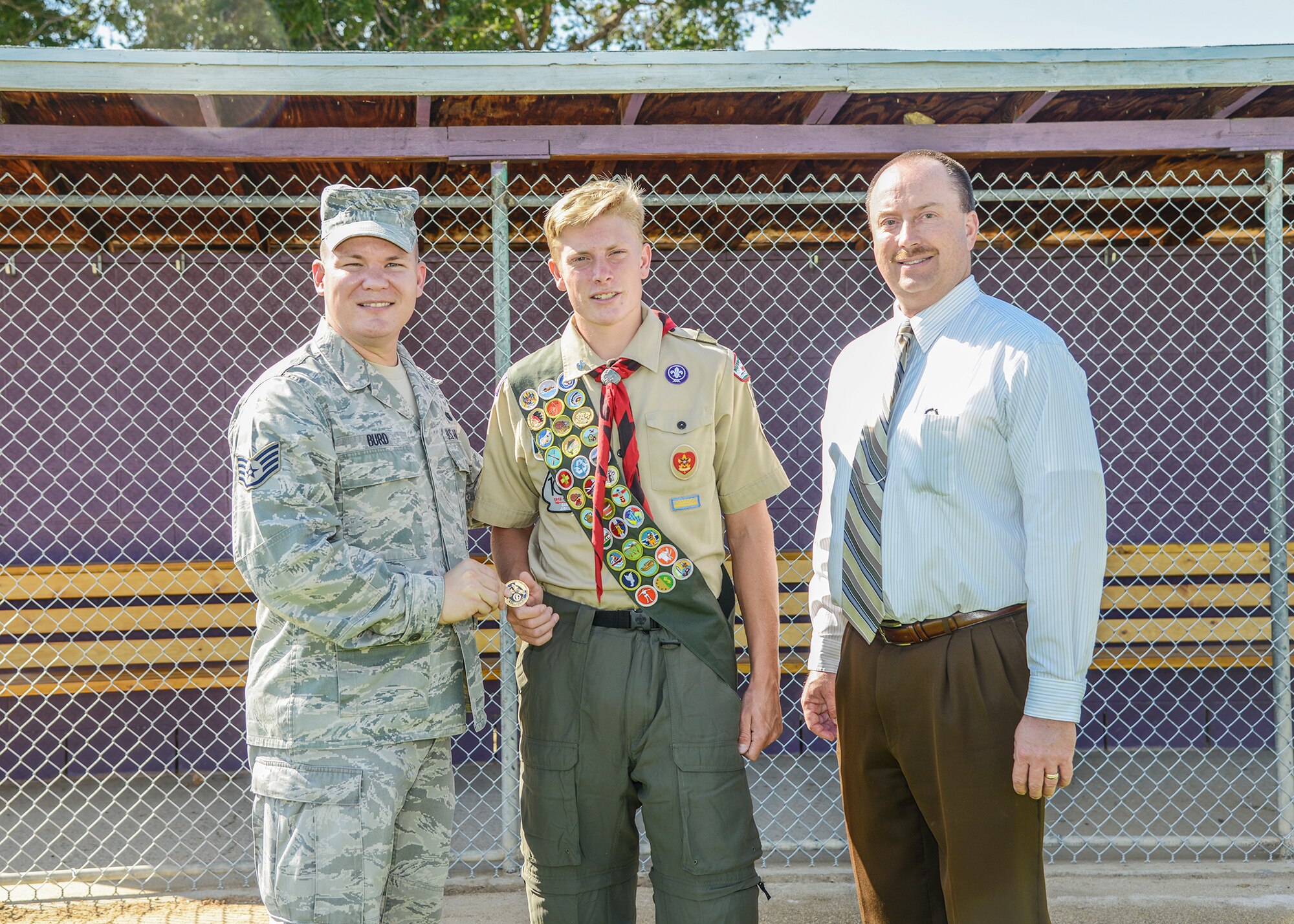 From left: Staff Sgt. Michael Burd, local Air Force Sergeants Association president, hands an AFSA coin to Wesley Nelson, an Eagle Scout and Desert High School senior, as principal Dr. David Ellms looks on. With donations from AFSA, Nelson was able to renovate DHS's baseball field dugouts.  (U.S. Air Force photo by Rebecca Amber) 