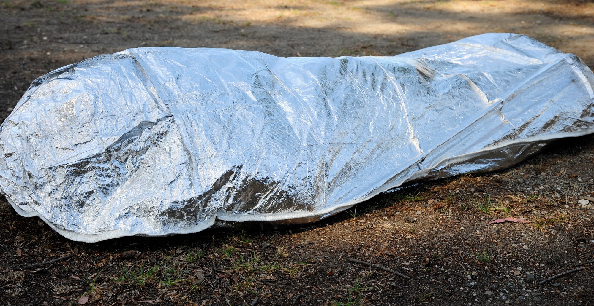 Senior Airman Ronald Skala, 30th Civil Engineer Squadron heavy equipment operator, demonstrates the use of a Fire Shelter, Sept. 21, 2015, Vandenberg Air Force Base, Calif. Constructed of aluminum foil, silica and fiberglass, a fire shelter is designed to protect the individual from smoke, heat and flames. (U.S. Air Force photo by Senior Airman Kyla Gifford/Released)