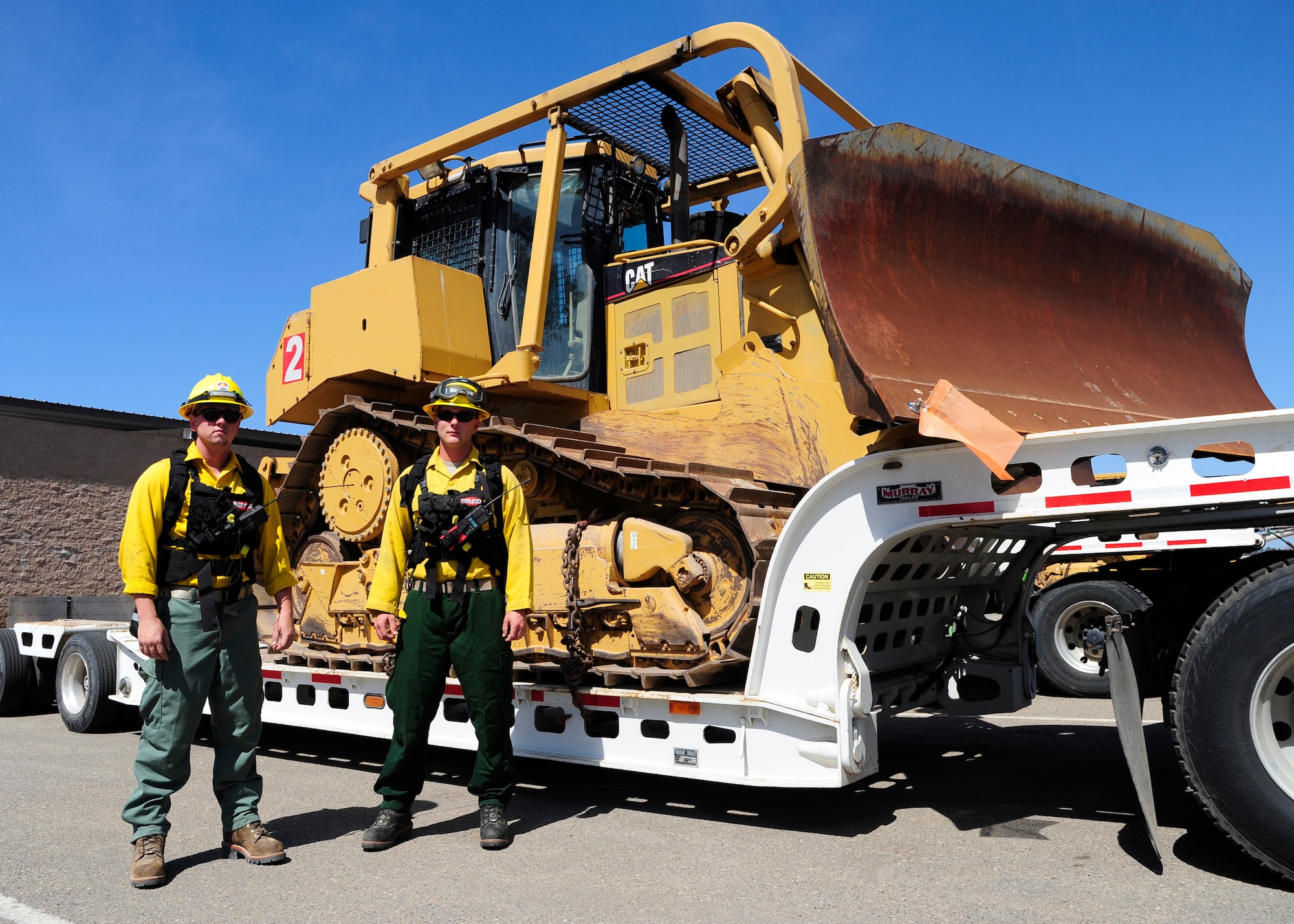 Senior Airmen Ronald Skala and Thomas Williams, 30th Civil Engineer Squadron heavy equipment operators, stand in front of a fire dozer, Sept. 21, 2015, Vandenberg Air Force Base, Calif. The fire dozer team is on stand-by during every launch, prepared to contain fires that start and prevent damage to base assets. (U.S. Air Force photo by Senior Airman Kyla Gifford/Released)