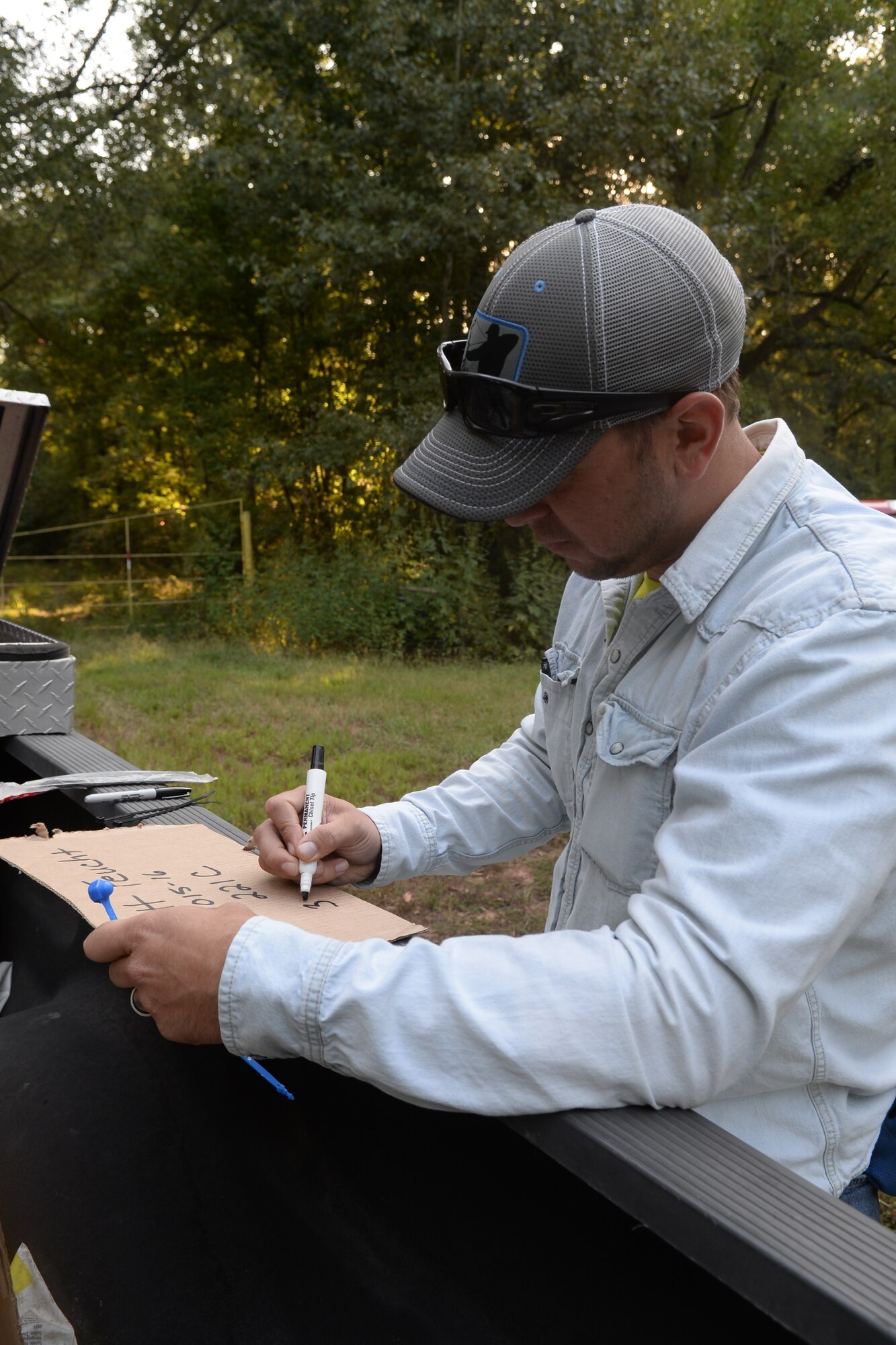Master Sgt. James Welch, 307th Safety explosives safety manager, writes on a piece of cardboard before placing it on a registered deer hunting location at Barksdale Air Force Base, La., Sept 15, 2015. On the first day of stand registration newcomers may register for a deer hunting location and people who hunted on base last year can move their stands to new locations. After registering, hunters have up to 48 hours to mark their locations.(U.S. Air Force photo/Senior Airman Amanda Morris)