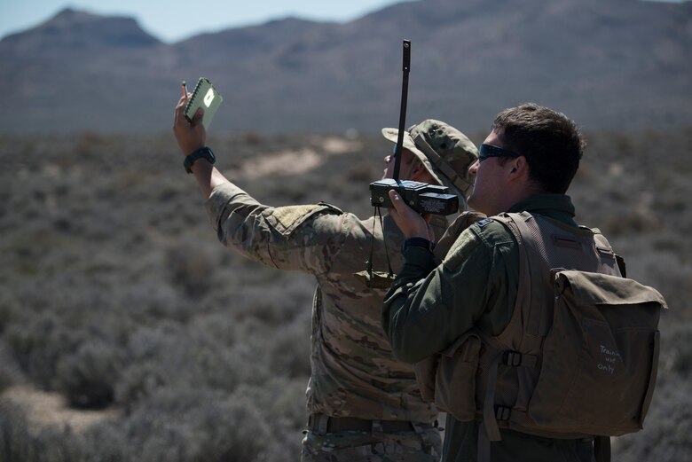 U.S. Air Force Senior Airman Dane Dougherty, 336 Training Group Survival, Evasion, Resistance and Escape specialist, demonstrates how to use a mirror flash while Capt. Jack Green, 480 Fighter Squadron F-16 pilot, uses a radio Jul 30, 2015 at the Nevada Test and Training Range, Nevada. Doughetry assisted and evaluated Green, who was simulating a downed pilot, during Red Flag 15-3. (U.S. Air Force photo by Senior Airman Brittany A. Chase)