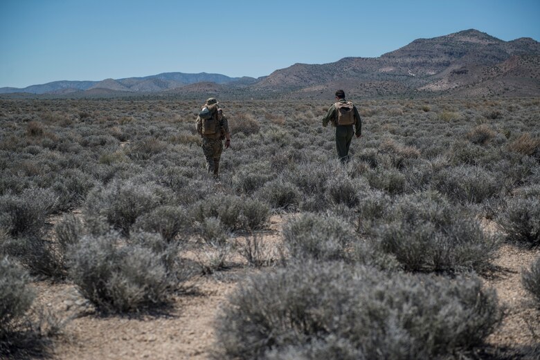 U.S. Air Force Senior Airman Dane Dougherty, 336 Training Group Survival, Evasion, Resistance and Escape specialist, and Capt. Jack Green, 480 Fighter Squadron F-16 pilot, walk through the desert Jul 30 at the Nevada Test and Training Range, Nevada. Doughetry assisted and evaluated Green, who was simulating a downed pilot, during Red Flag 15-3. (U.S. Air Force photo by Senior Airman Brittany A. Chase)