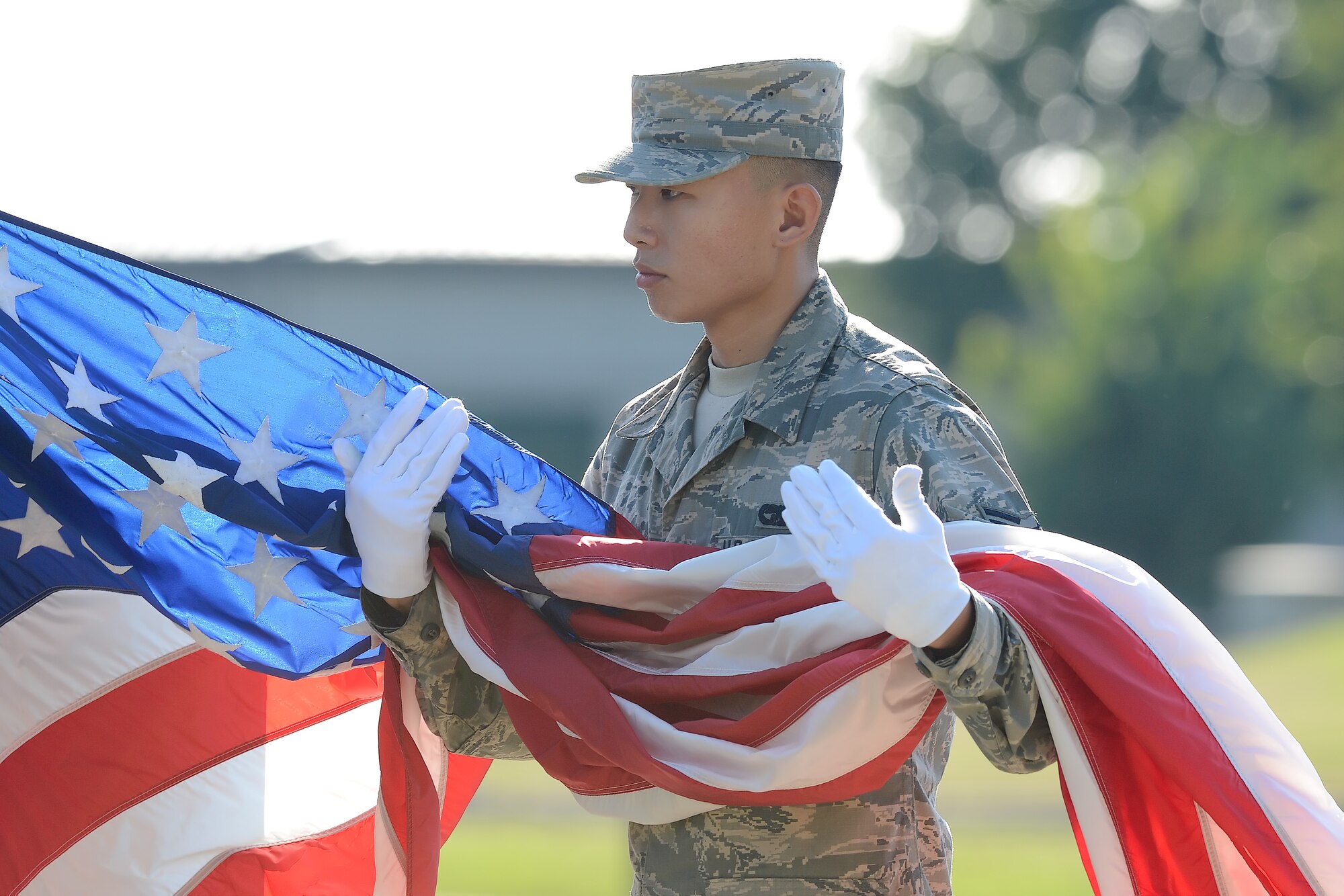 Airman 1st Class Minsoo Goh, 436th Aerial Port Squadron ramp services specialist, cradles the American flag after it was lowered from the main flag pole during the National POW/MIA Recognition Day formal retreat ceremony Sept. 18, 2015, on Dover Air Force Base, Del. Goh was part of an honor guard team at the center of the ceremony. (U.S. Air Force photo/Greg L. Davis)