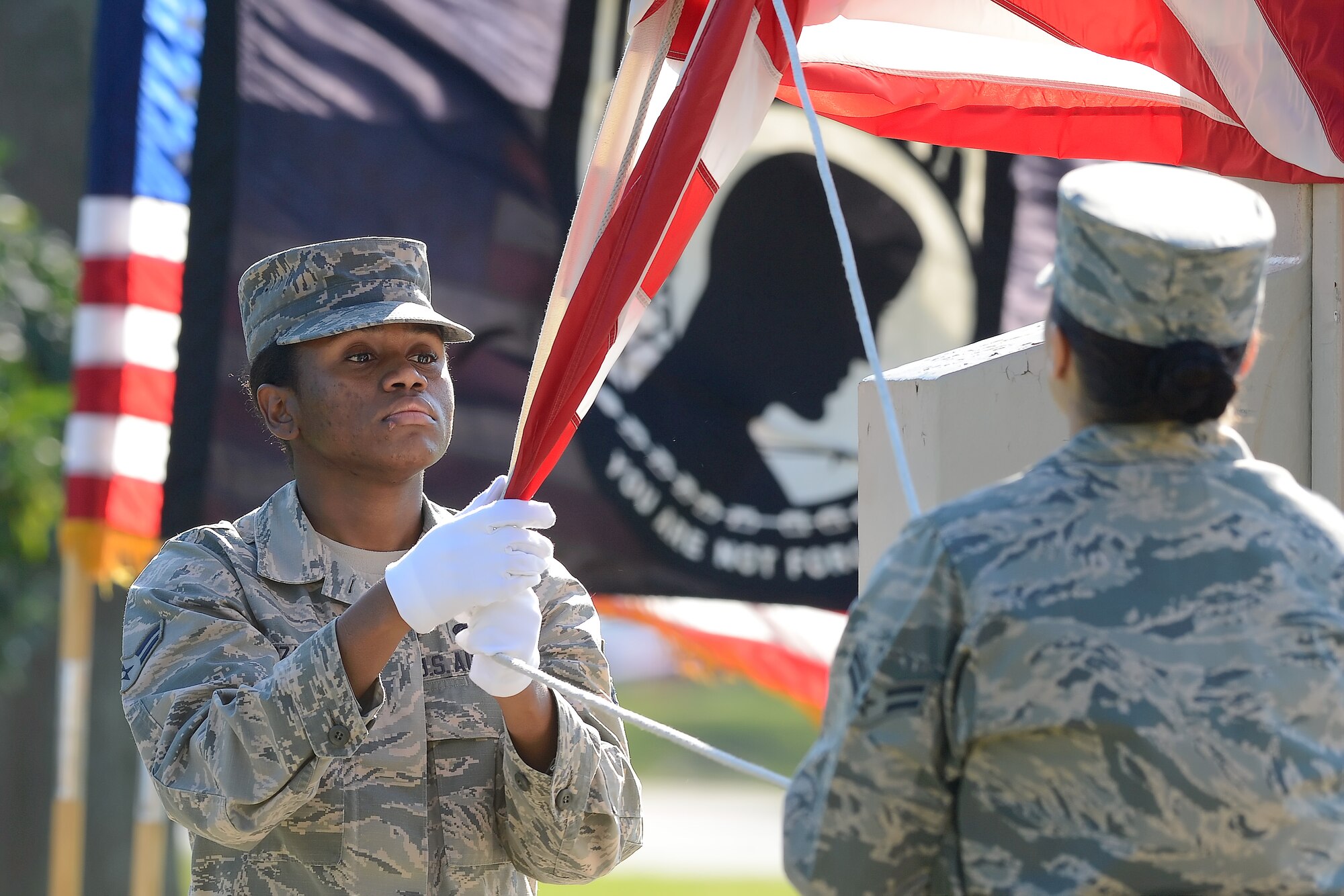 Airman 1st Class Monique Lozano, 436th Aerial Port Squadron, grabs the edge of the American flag as it is lowered from the base flagpole during the National POW/MIA Recognition Day on Sept. 18, 2015, on Dover AFB, Del. Team Dover conducted a formal retreat ceremony attended by members of Team Dover along with civic and military leaders. (U.S. Air Force photo/Greg L. Davis)