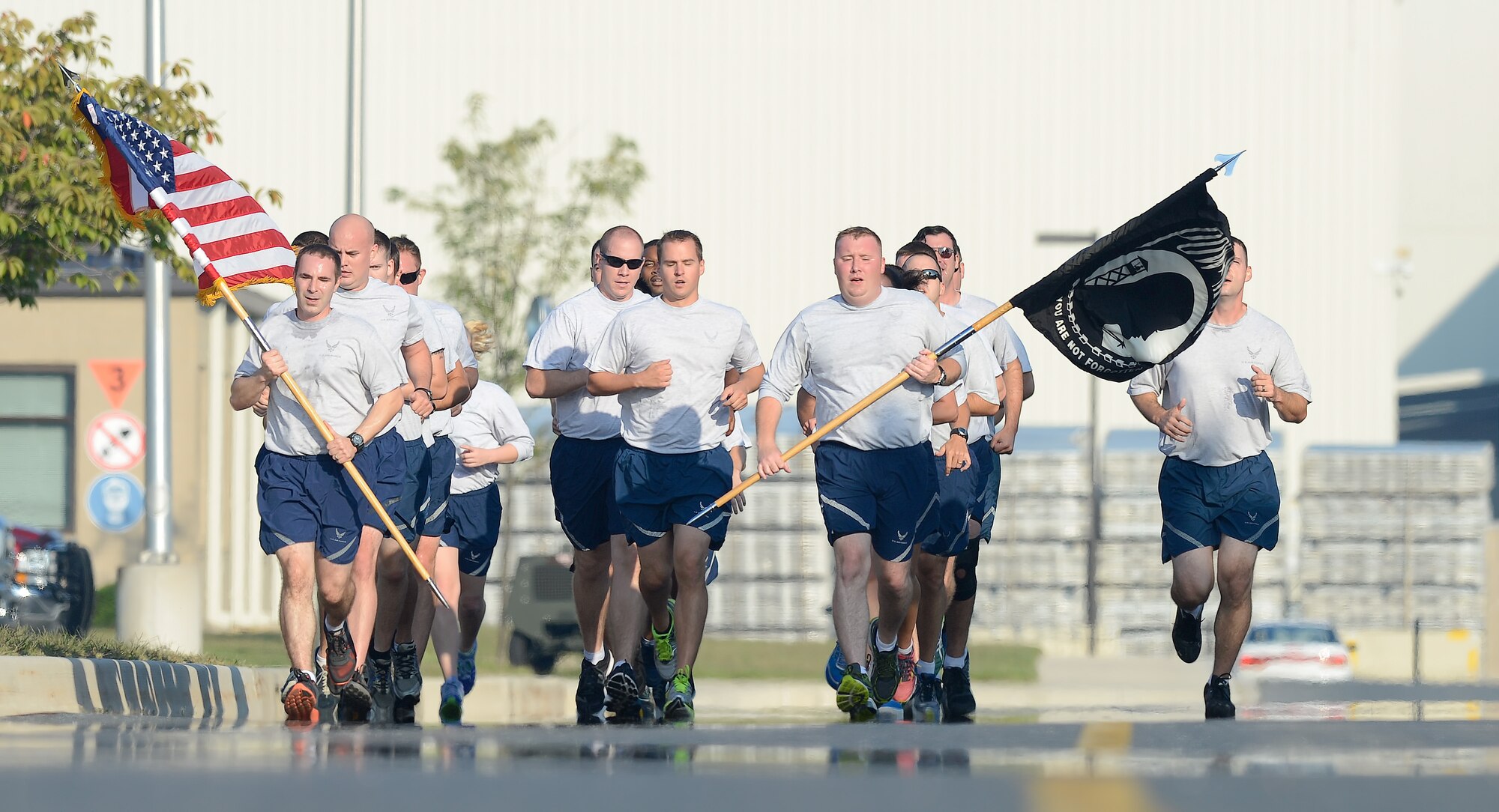 Members from the 436th Airlift Wing run in formation as the American and POW/MIA flags are carried during the National POW/MIA Recognition Day run on Sept. 18, 2015, on Dover Air Force Base, Del. Team Dover conducted the run along with a formal retreat ceremony which included the reading of names of those identified by the Armed Forces Mortuary Affairs Service; a tenant unit at Dover, during the past year. (U.S. Air Force photo/Greg L. Davis)