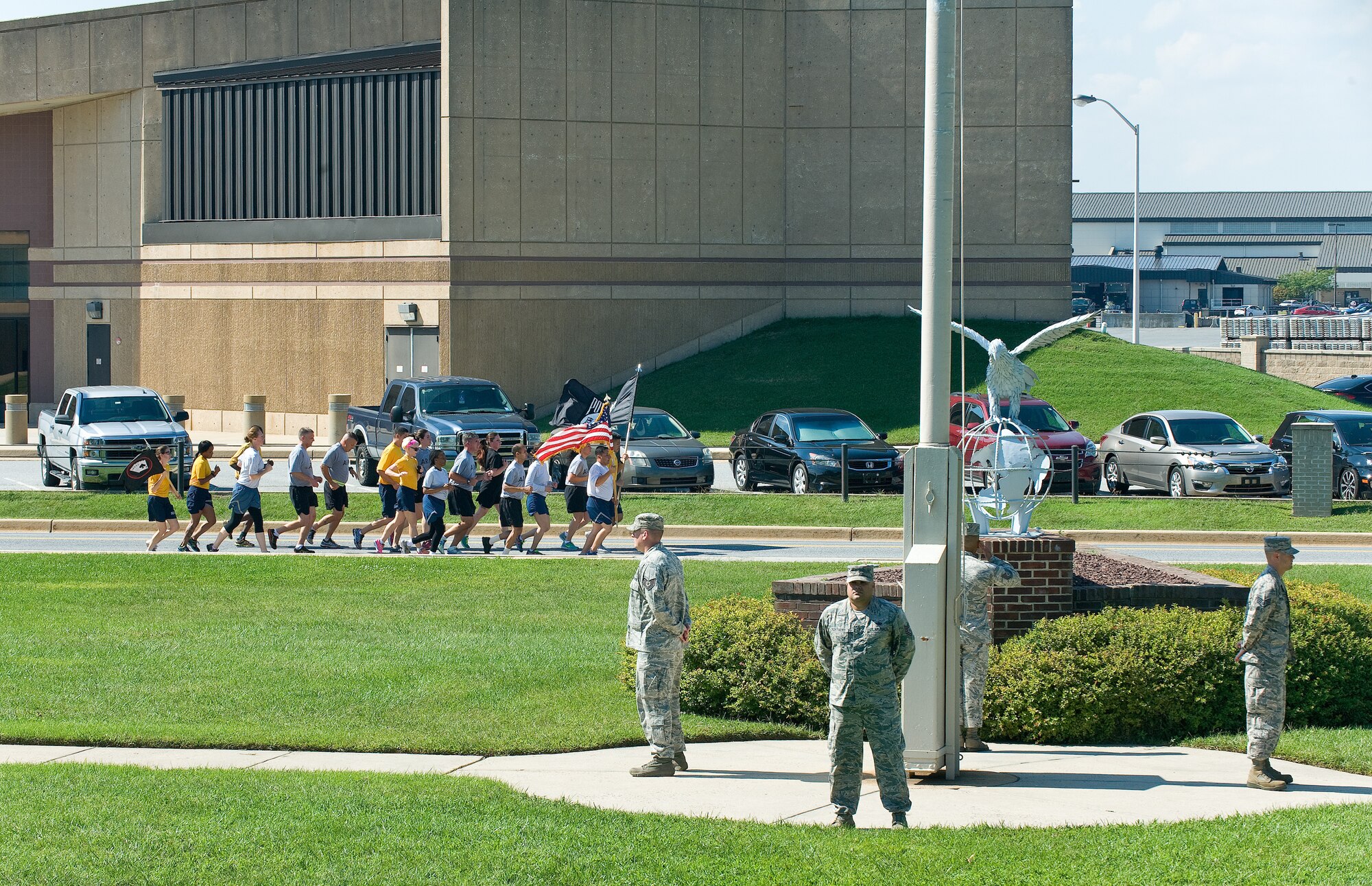 A Team Dover four-person detail stands vigilant as members of the Armed Forces Medical Examiner System run by with the U.S. and POW/MIA flags during the National POW/MIA Recognition Day vigil Sept. 18, 2015, at Dover Air Force Base, Del. Numerous four-person details stood guard at the base flag pole in 10-minute increments as one member of the detail saluted the U.S. flag every time it passed by. (U.S. Air Force photo/Roland Balik) 