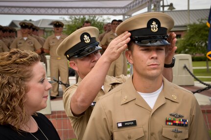 Chief Machinist’s Mate Jody Greenhill places a cover on Chief Electronics Technician (Select) Andrew Pfeffer as he is advanced to the rank of Chief Petty Officer during the Naval Nuclear Power Training Command Fiscal Year 2016 Chief Pinning Ceremony September, 16, 2015. Staff, students, family and friends watched as Pfeffer and 28 other Chief Selects donned anchors for the first time. (U.S. Navy photo/Mass Communication Specialist 2nd Class Jason Pastrick)