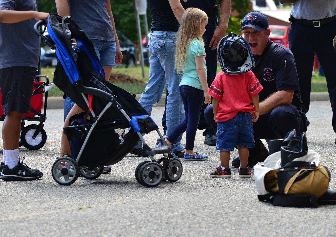 Aaron Sherman, Fort Eustis Fire Department fire fighter, interacts with children during the Fall Festival at Fort Eustis, Va., Sept. 19, 2015. The fire department talked about fire safety and also had a truck on display, which children were able to see the inside of. (U.S. Air Force photo by Staff Sgt. Natasha Stannard/Released)