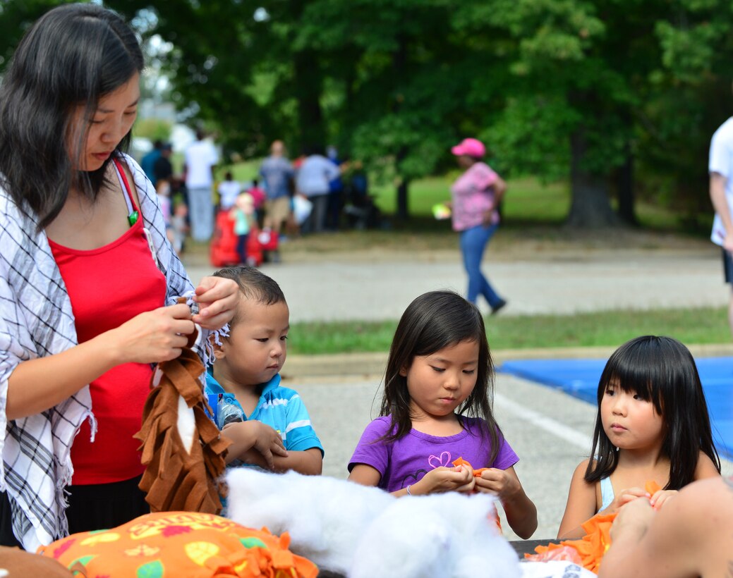Christine Hsiau, wife of U.S. Army Capt. James Hsiau, helps her children put together crafts at the Fall Festival at Fort Eustis, Va., Sept. 19, 2015. The Youth Programs center hosted the festival in conjunction with base agencies to highlight safety initiatives and promote networking for school-age-children and their families. (U.S. Air Force photo by Staff Sgt. Natasha Stannard/Released)