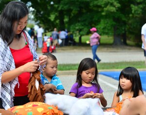 Christine Hsiau, wife of U.S. Army Capt. James Hsiau, helps her children put together crafts at the Fall Festival at Fort Eustis, Va., Sept. 19, 2015. The Youth Programs center hosted the festival in conjunction with base agencies to highlight safety initiatives and promote networking for school-age-children and their families. (U.S. Air Force photo by Staff Sgt. Natasha Stannard/Released)