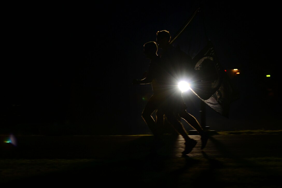Runners take part in a 24-hour Prisoner of War/Missing in Action vigil at Langley Air Force Base, Va., Sept. 17, 2015. Whether participants ran or walked, they carried the flag, keeping it in motion at all times during the vigil. (U.S. Air Force photo by Senior Airman Kimberly Nagle/Released) 