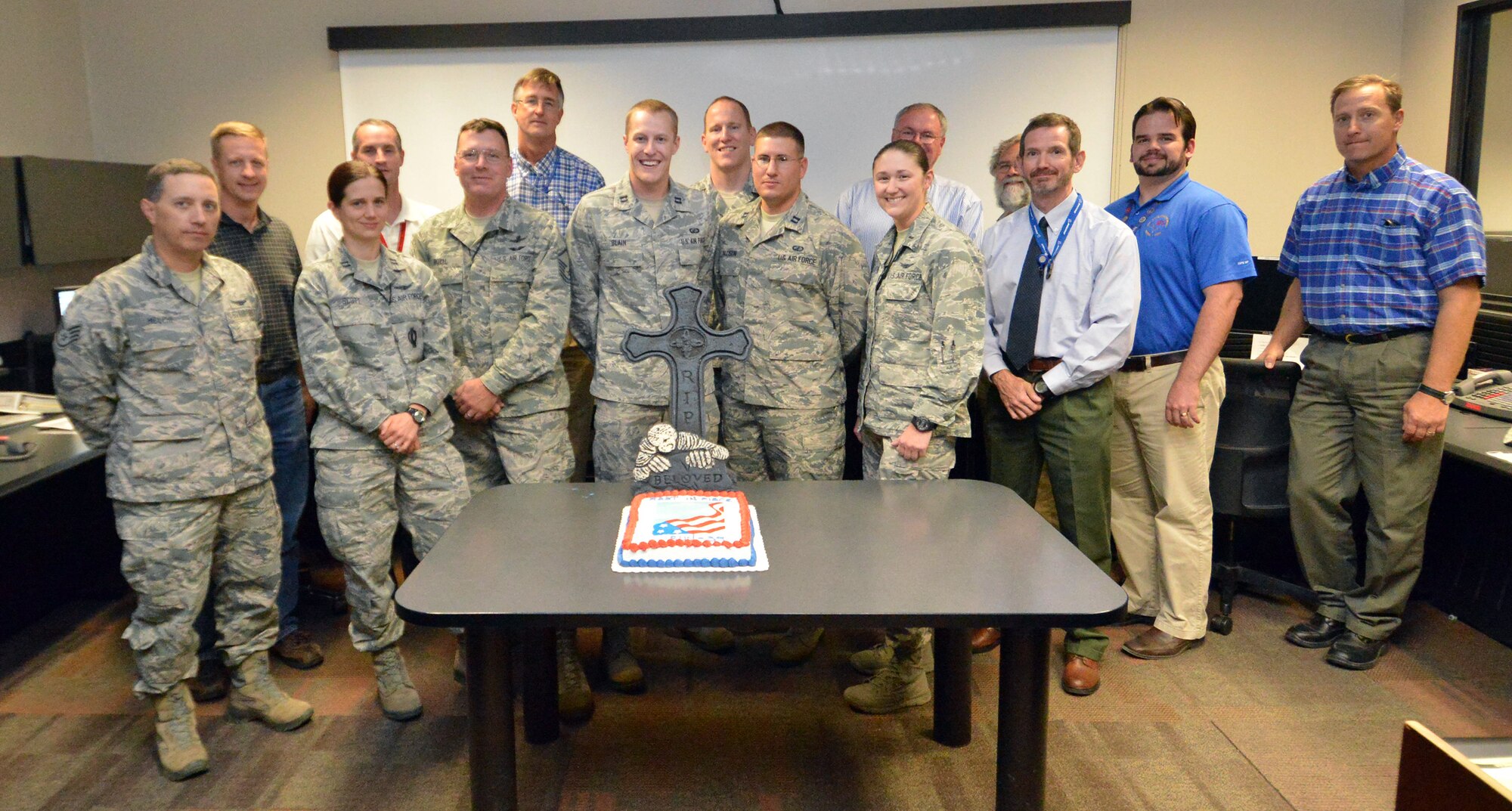 Members of the SVN-39 disposal team from the 2nd, 19th and 22nd Space Operations Squadrons, 50th Network Operations Group, Aerospace Corporation and Boeing await cake on the 2 SOPS operations floor after at Schriever Air Force Base, Colorado, the ceremonial final command was sent to SVN-39 at the completion of the vehicle’s disposal Monday, Sept. 21, 2015. SVN-39 was in operational orbit for almost 23 years – three times its original design life. (U.S. Air Force photo/Staff Sgt. Debbie Lockhart)