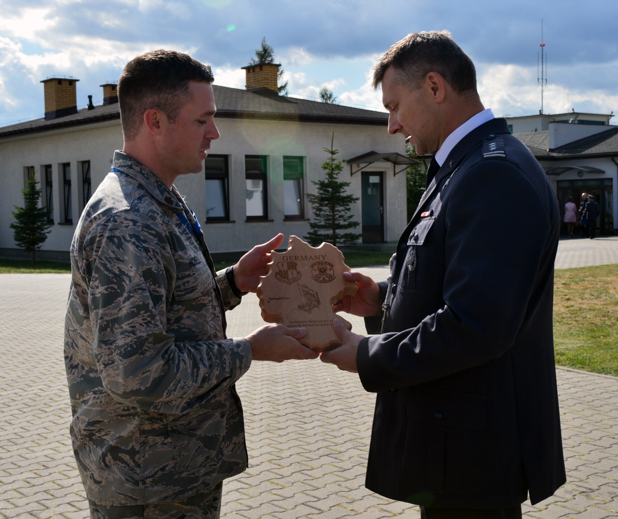 U.S. Air Force Maj. Christopher Howell, director of mission support for the 606th Air Control Squadron in Poland, presents Krzesiny Air Base Commander Colonel Grzegorz Ślusarz with a plaque as a token of appreciation during the Feast of the 31st Tactical Air Base Poznań-Krzesiny at Krzesiny Air Base, Poland Sept. 5, 2015. Krzesiny Air Base is hosting one of two operating locations for the 606th ACS during Aviation Detachment Rotation 15-4. (U.S. Air Force photo by 2nd Lt. Meredith Mulvihill/Released)