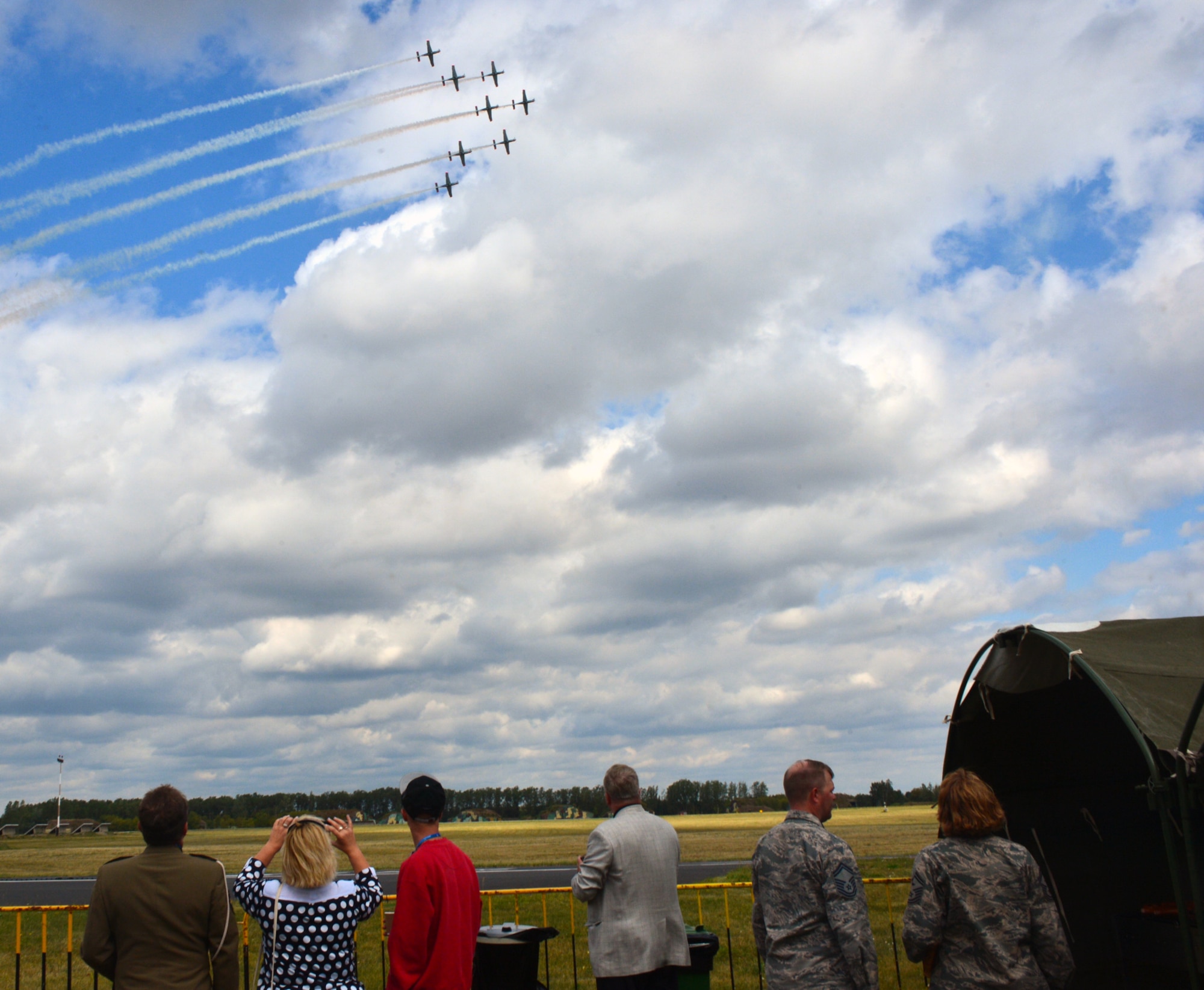 Two U.S. Airmen watch an aerial demonstration alongside other attendees during the Feast of the 31st Tactical Air Base Poznań-Krzesiny at Krzesiny Air Base, Poland Sept. 5, 2015. The celebration included an air show with several demonstration teams, including an exhibition by a Polish F-16 Fighting Falcon fighter aircraft. (U.S. Air Force photo by 2nd Lt. Meredith Mulvihill/Released)