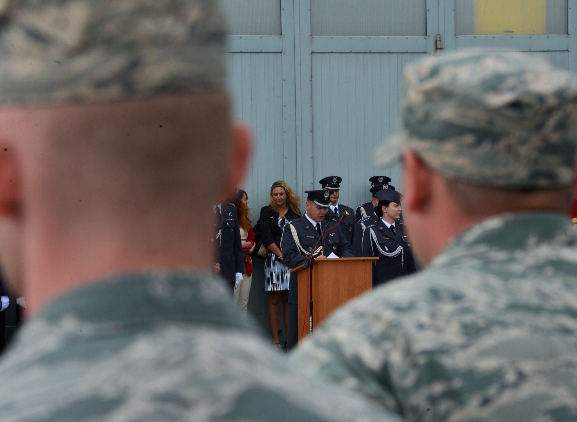 Airmen from the 606th Air Control Squadron listen to a member of the Polish 31st Tactical Air Base speak during the Feast of the 31st Tactical Air Base Poznań-Krzesiny at Krzesiny Air Base, Poland Sept. 5, 2015. The ceremony marks the 61st anniversary of members of the Polish Air Forces being stationed at Krzesiny Air Base.  (U.S. Air Force photo by 2nd Lt. Meredith Mulvihill/Released)