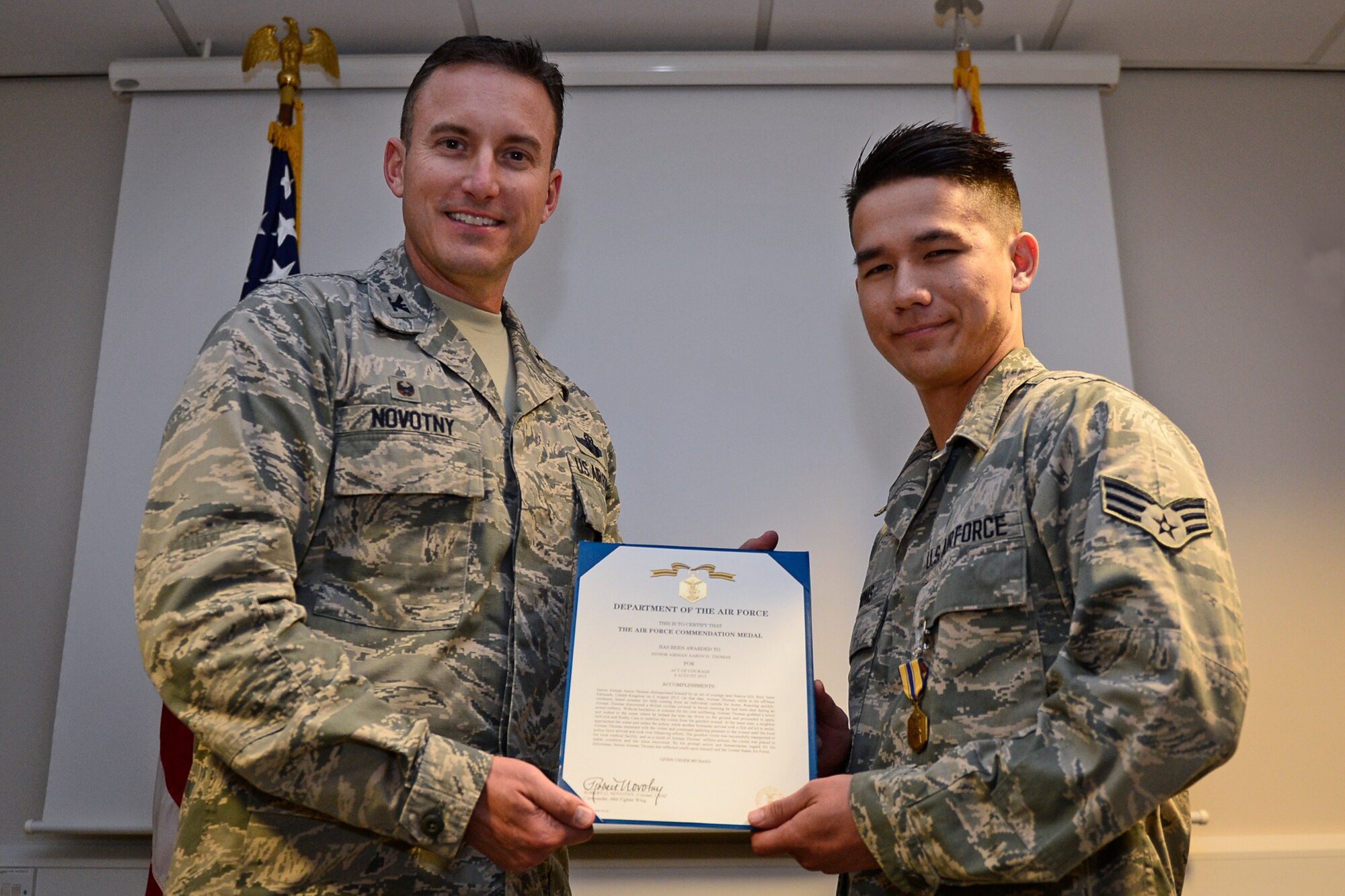 Col. Robert Novotny, 48th Fighter Wing commander, presents the Air Force Commendation Medal to Senior Airman Aaron Thomas, 48th Contracting Squadron contracting specialist, at Royal Air Force Lakenheath, England, Sept. 23. Thomas courageously helped to save a gunshot victim in Bury St. Edmunds, Aug. 4, 2015. (U.S. Air Force photo by Airman 1st Class Erin R. Babis/Released)