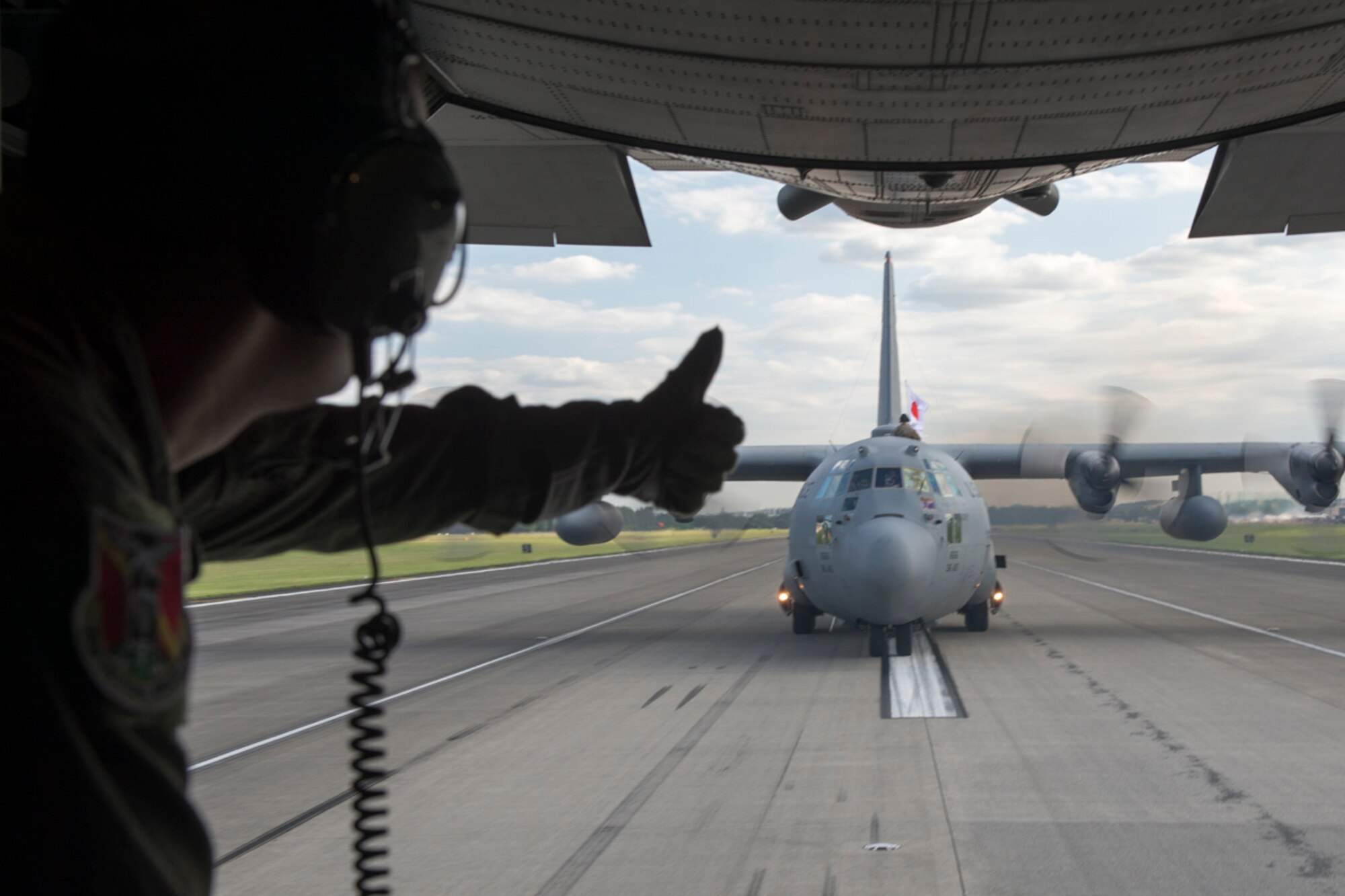 US Air Force Staff. Sgt. Gary Patterson, 36th Airlift Squadron loadmaster, gives a thumbs-up to aircrew on a C-130 Hercules during the 2015 Japanese-American Friendship Festival at Yokota Air Base, Japan, Sept. 20, 2015. A service member on Patterson's C-130 displayed a US flag while the tailing aircraft displayed the Japanese flag, highlighting the festival's theme--strengthening the US-Japan partnership. (U.S. Air Force photo by Staff Sgt. Cody H. Ramirez/Released)
