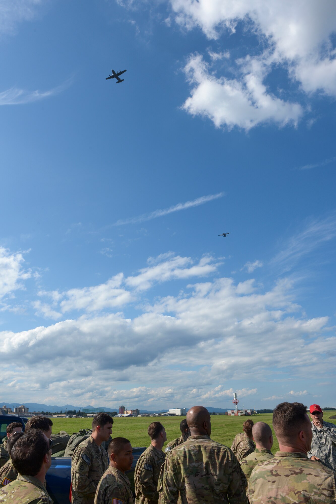 Two C-130 Hercules with the 36th Airlift Squadron fly above Soldiers with the 1st Battalion, 1st Special Operations Group (Airborne), after conducting a personnel air drop during the 2015 Japanese-American Friendship Festival at Yokota Air Base, Japan, Sept. 19, 2015. The jump displayed Yokota's airdrop capability to the festival attendees while also allowing the Airborne members to receive scheduled training and update jump currency. (U.S. Air Force photo by Staff Sgt. Cody H. Ramirez/Released)