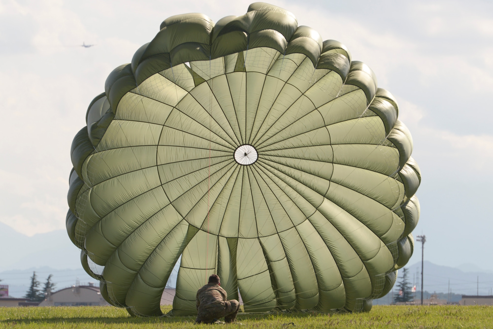 A Soldier with the 1st Battalion, 1st Special Operations Group (Airborne), secures his parachute after jumping from a C-130 Hercules during the 2015 Japanese-American Friendship Festival at Yokota Air Base, Japan, Sept. 19, 2015. More than 40 Soldiers jumped during the two-day festival, demonstrating Yokota's airdrop capability to the festival attendees. (U.S. Air Force photo by Staff Sgt. Cody H. Ramirez/Released)