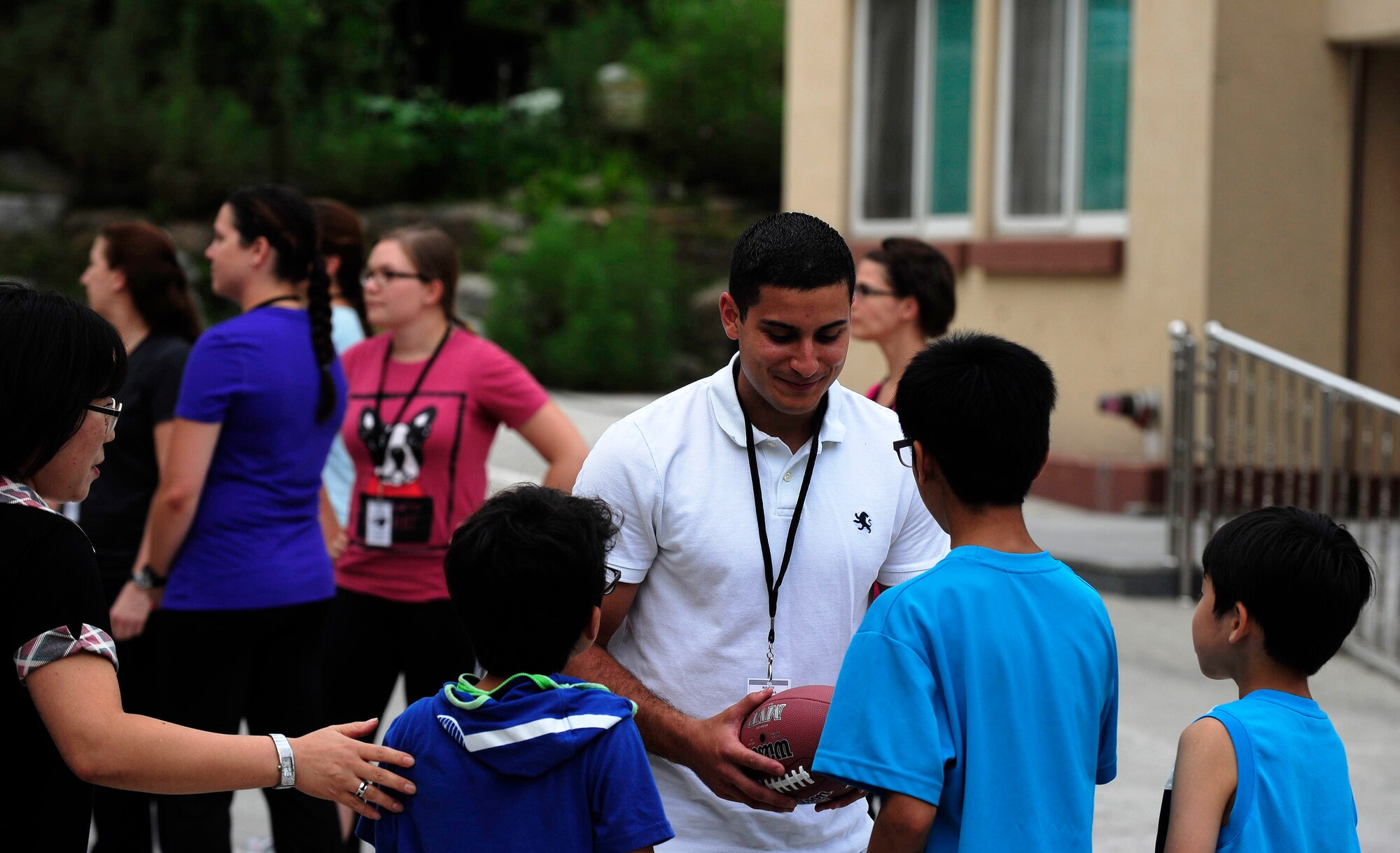 Senior Airman Christian Ruiz, 8th Maintenance Squadron aircraft electrical and environmental systems technician, Kunsan Air Base, Republic of Korea, teaches children from a Welfare Facility how to play football at Gunsan City, ROK, Aug. 18, 2015. The 8th Fighter Wing chapel sets up monthly visits to the facility where Airmen can play games and socialize with the children. (U.S. Air Force photo by Staff Sgt. Nick Wilson/Released) 