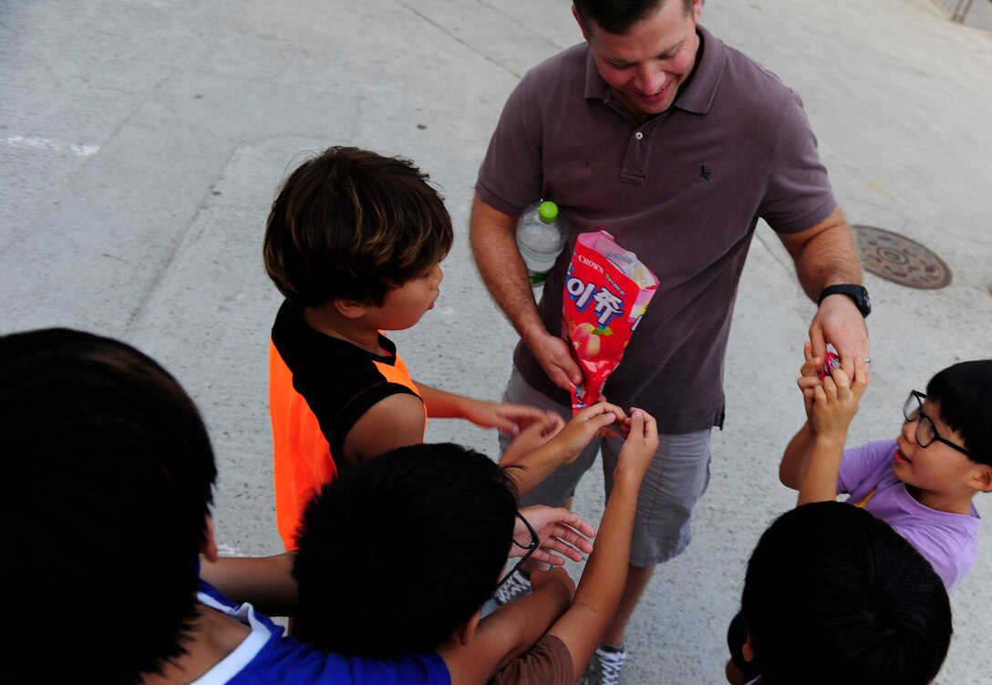 Tech. Sgt. Danny Plunkett, 8th Logistics Readiness Squadron vehicle maintenance shop foreman, Kunsan Air Base, Republic of Korea, passes out candy to children at an orphanage in Gunsan City, ROK, Sept. 1. 2015. More than 60 children live in the orphanage where the Airman volunteered. (U.S. Air Force photo by Staff Sgt. Nick Wilson/Released)