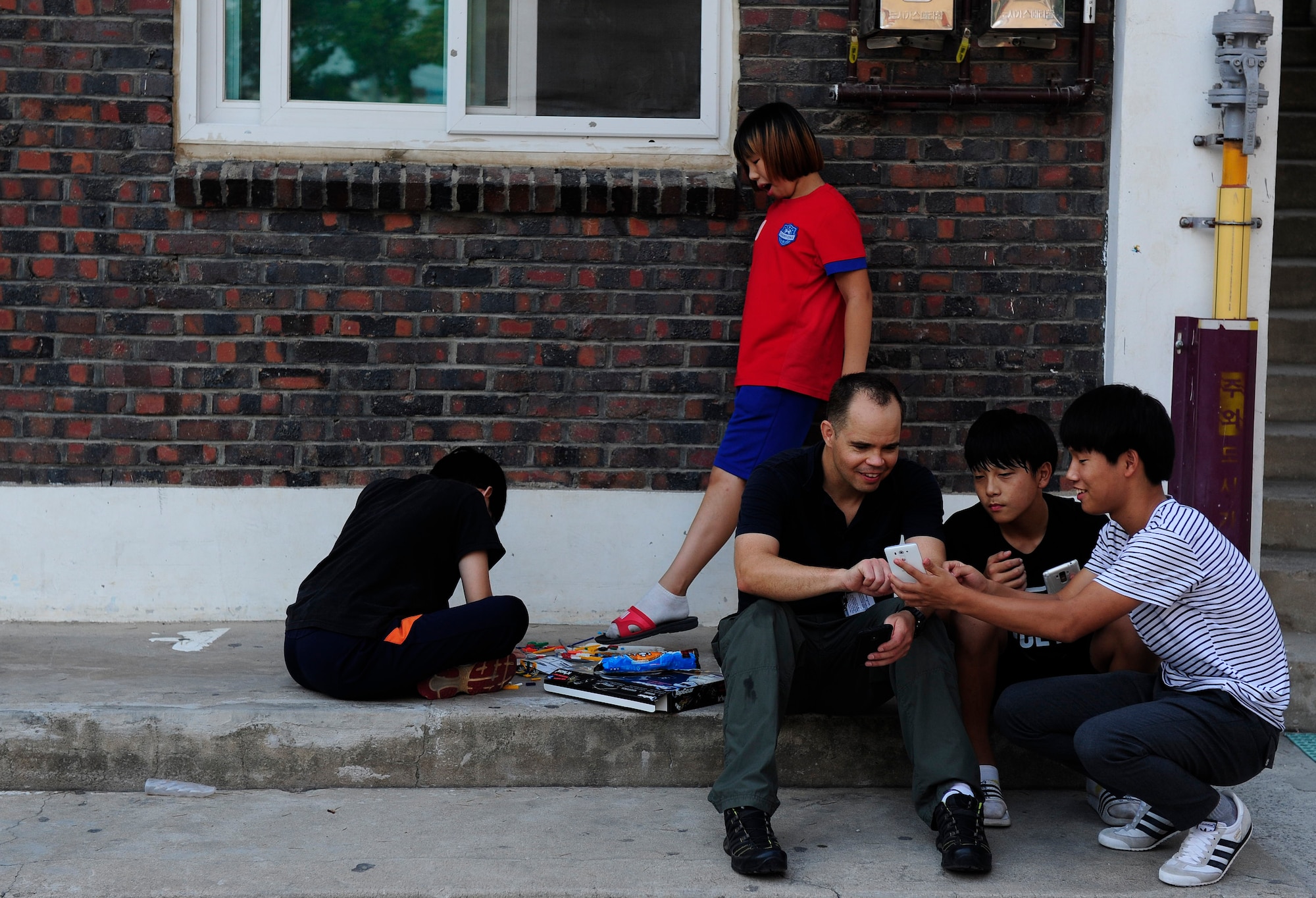 Lt. Col. Brandon Eskam, 175th Expeditionary Fighter Squadron inspector general, South Dakota Air National Guard, plays cellular games with children at a Welfare Facility in Gunsan City, ROK, Sept. 1. 2015. The volunteer program helps Airmen develop leadership skills and become positive role models within the community. (U.S. Air Force photo by Staff Sgt. Nick Wilson/Released)