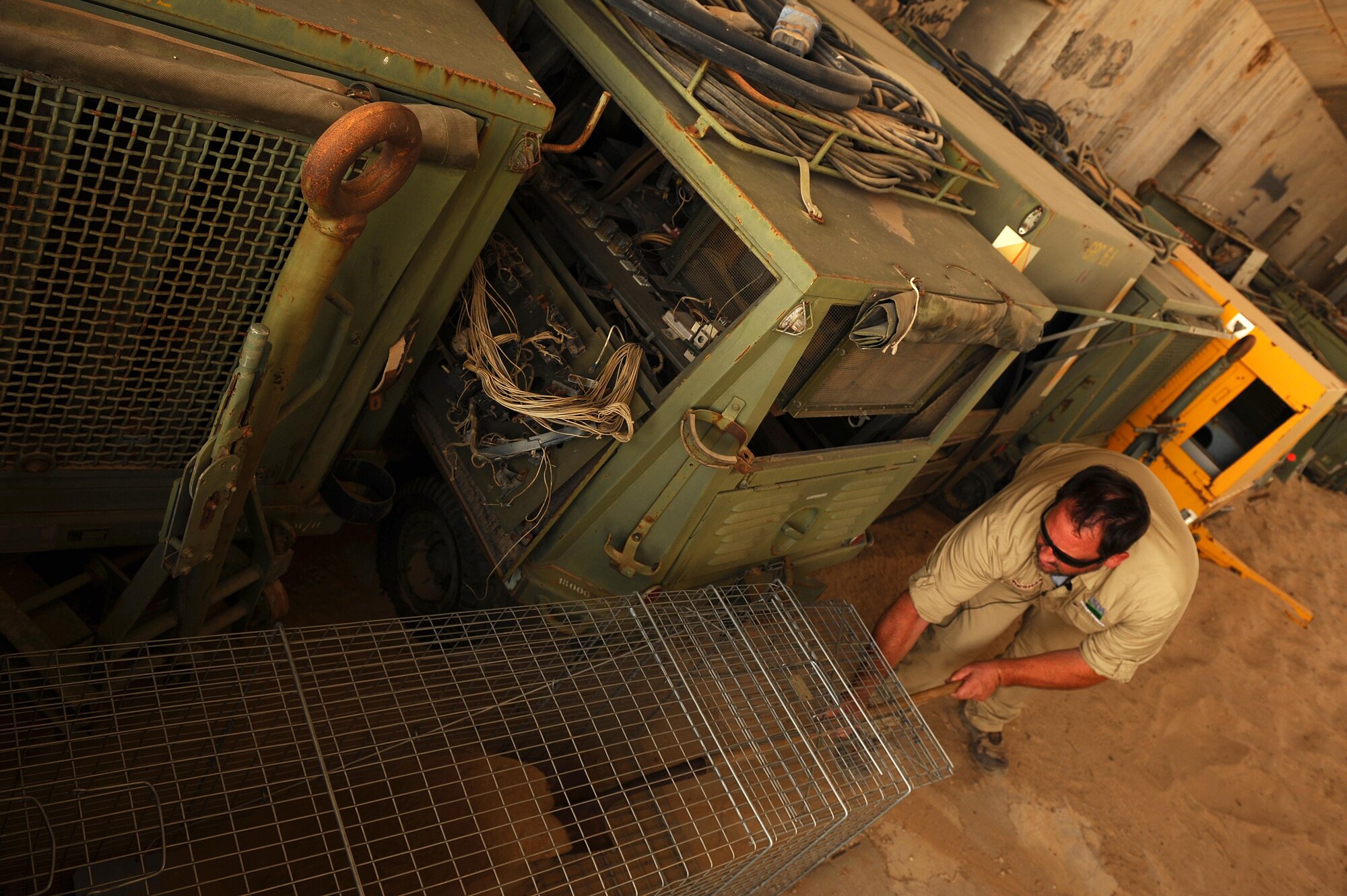 Dave Tresham, United States Department of Agriculture wildlife biologist, assembles a trapping device near the flightline at an undisclosed location in Southwest Asia, Sept. 3, 2015. Tresham controls the wildlife population in the area through the use of ballistics, habitat modification and education in an effort to reduce aircraft strikes that can hamper the support the 386th Air Expeditionary Wing provides to degrade and defeat the Islamic State during Operation Inherent Resolve. (U.S. Air Force photo/Tech. Sgt. Brittany E. Jones)