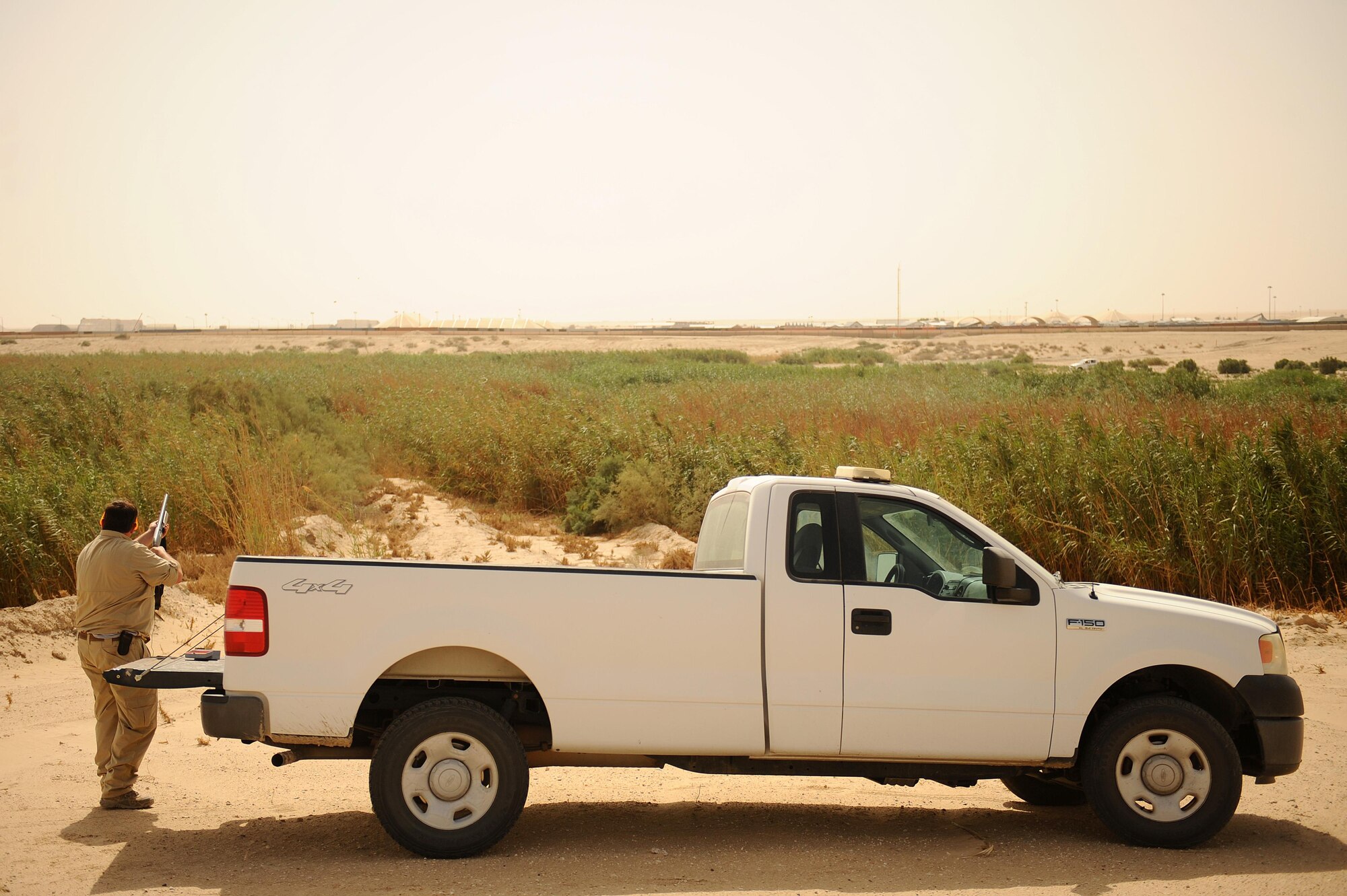 Dave Tresham, United States Department of Agriculture wildlife biologist, disperses birds settling in an area known as the "Green Mile," a manmade sewage runoff expanse with a lush, green environment that provides food, water and shelter attractive to wild animals at an undisclosed location in Southwest Asia, Sept. 3, 2015. Tresham uses ballistics multiple times per day to frighten birds and other creatures away to minimize the strike hazard to aircraft supporting the mission to destroy and degrade the Islamic State.  (U.S. Air Force photo/Tech. Sgt. Brittany E. Jones)
 	
