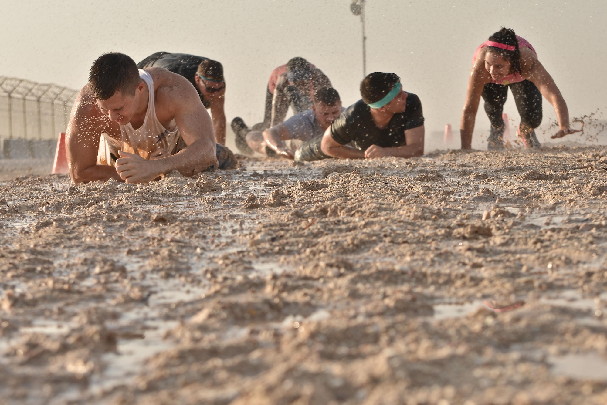 Diversity Day Mud Run participants low crawl through a mud pit to continue the race September 20, 2015 at Al Udeid Air Base, Qatar. The mud run challenged 106 runners with a two mile course that contained several obstacles from low crawling, T-wall climbing, barrier hurdles, and a Ôdeep freezeÕ cold mud pool. The event was held to help spread the word of Diversity Day, an initiative started by the Department of Defense for diversity events held throughout the year. (U.S. Air Force photo/ Staff Sgt. Alexandre Montes)