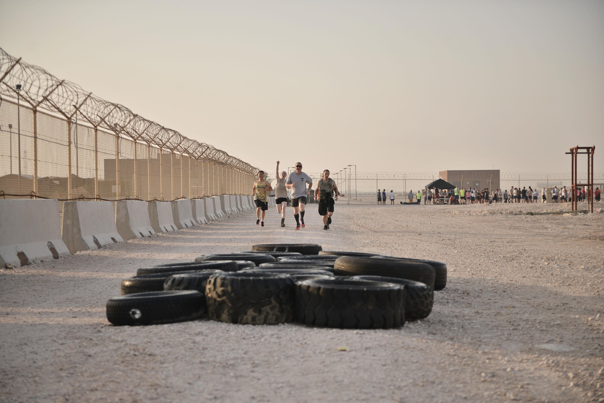 Participants approach a tire obstacle during a Diversity Day Mud Run September 20, 2015 at Al Udeid Air Base, Qatar. The mud run challenged 106 runners with a two mile course that contained several challenges from low crawling, a T-wall climb, barrier hurdles, and a Ôdeep freezeÕ cold mud pool. The event was held to help spread the word of Diversity Day, an initiative started by the Department of Defense for diversity events held throughout the year. (U.S. Air Force photo/ Staff Sgt. Alexandre Montes)