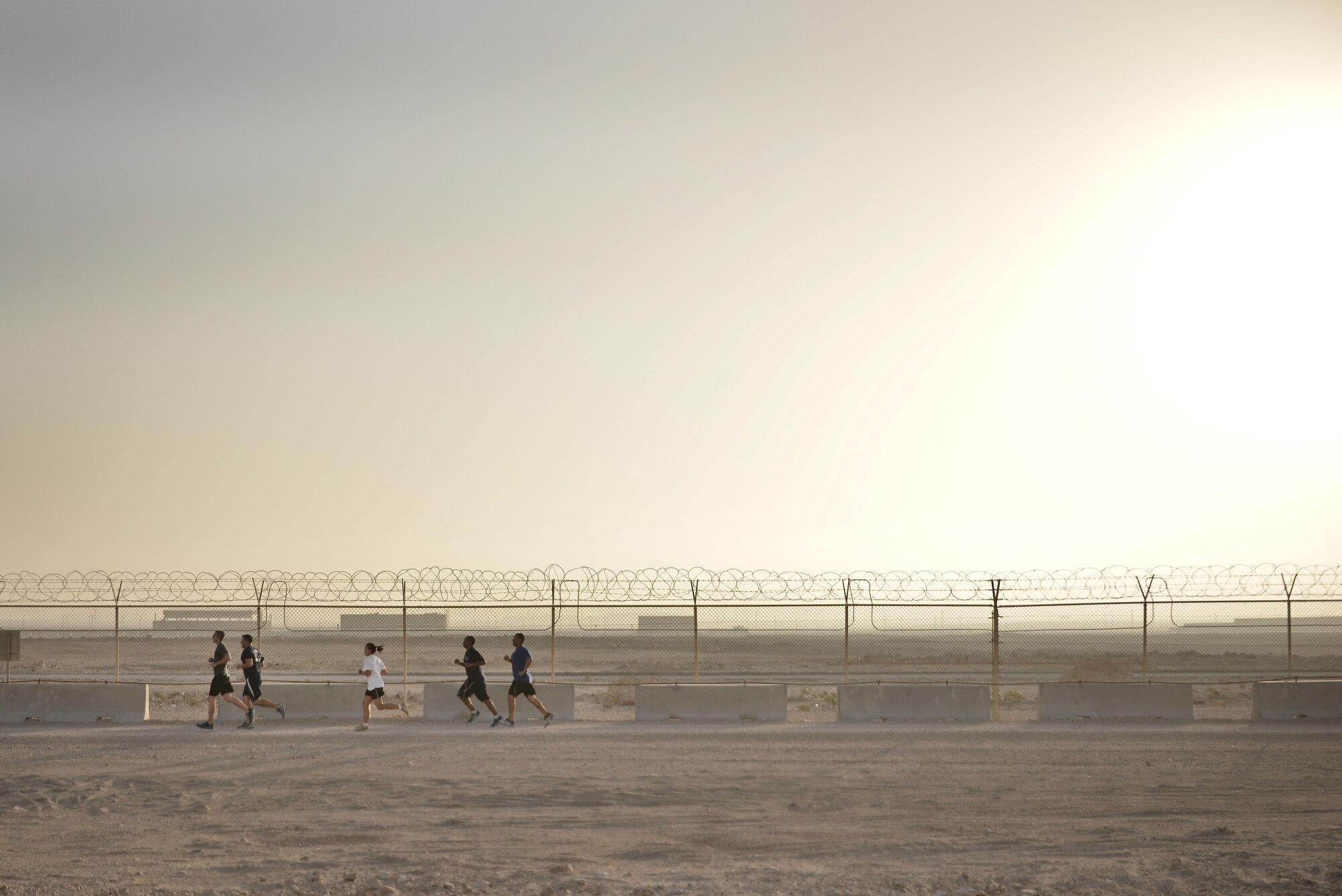 Diversity Day Mud Run participants clear a section of their two mile course September 20, 2015 at Al Udeid Air Base, Qatar. The mud run challenged 106 runners with several obstacles from low crawling, T-wall climbing, barrier hurdles, and a Ôdeep freezeÕ cold mud pool. The event was held to help spread the word of Diversity Day, an initiative started by the Department of Defense for diversity events held throughout the year. (U.S. Air Force photo/ Staff Sgt. Alexandre Montes)