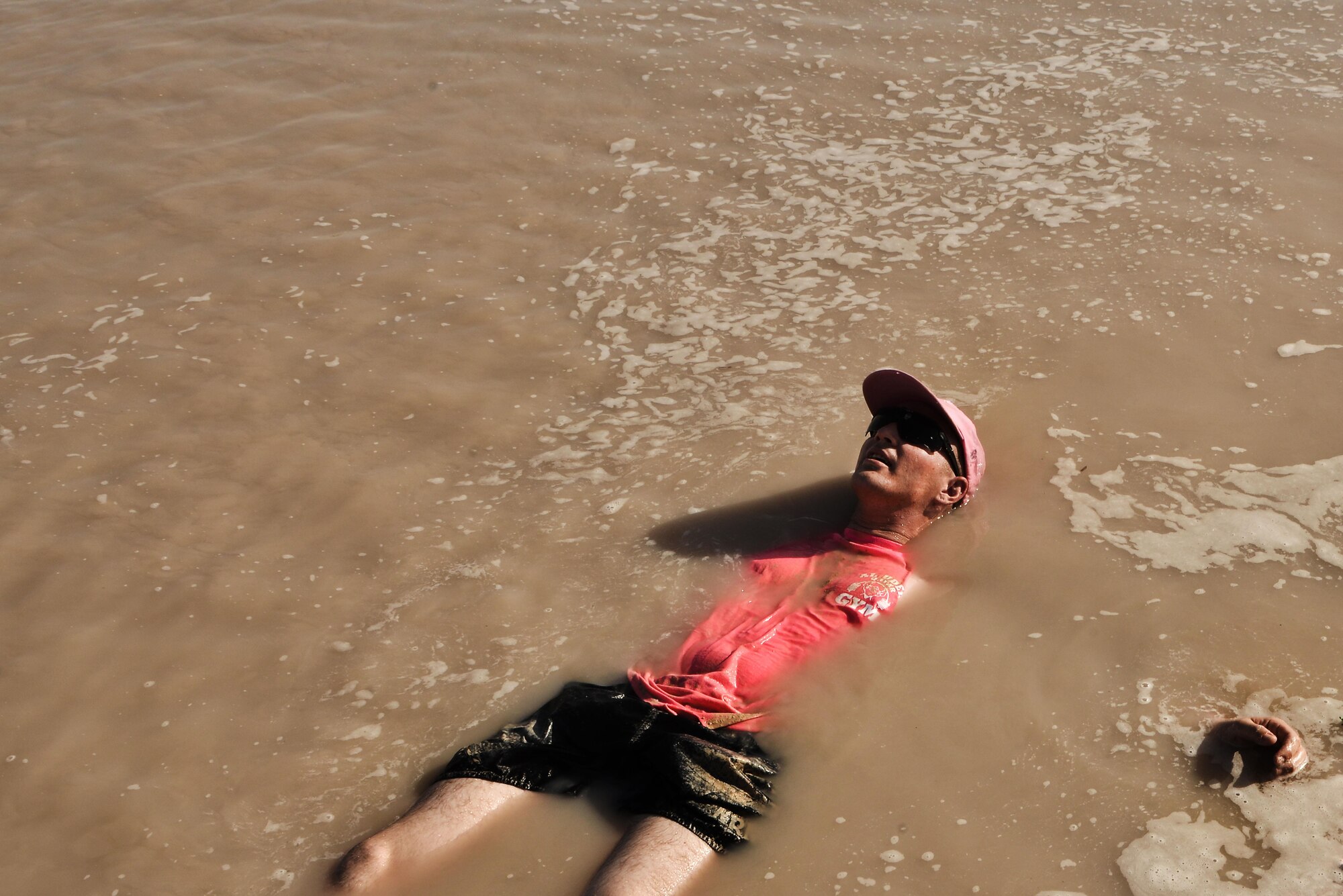 U.S. Army Sgt. Jeremy Bergstrom, 2nd Battalion, 43rd Air Defense Artillery Regiment, lies in a cool pool of mud after completing a Diversity Day mud run September 20, 2015 at Al Udeid Air Base, Qatar. The mud run challenged 106 runners with several obstacles from low crawling, T-wall climbing, barrier hurdles, and a Ôdeep freezeÕ cold mud pool. The event was held to help spread the word of Diversity Day, an initiative started by the Department of Defense for diversity events held throughout the year. (U.S. Air Force photo/ Staff Sgt. Alexandre Montes)