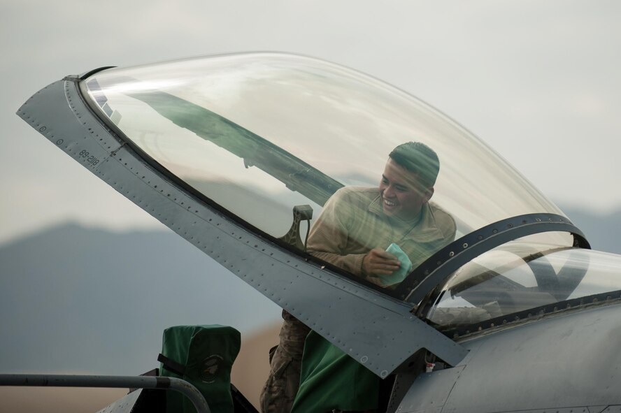 U.S. Air Force Airman 1st Class Jay Chhoeun, assigned to the 455th Expeditionary Maintenance Squadron, talks with other Airmen as he cleans the canopy of an F-16 Fighting Falcon aircraft at Bagram Airfield, Afghanistan, Sept. 22, 2015. The F-16 is a multi-role fighter aircraft that is highly maneuverable and has proven itself in air-to-air and air-to-ground combat. (U.S. Air Force photo by Tech. Sgt. Joseph Swafford/Released)