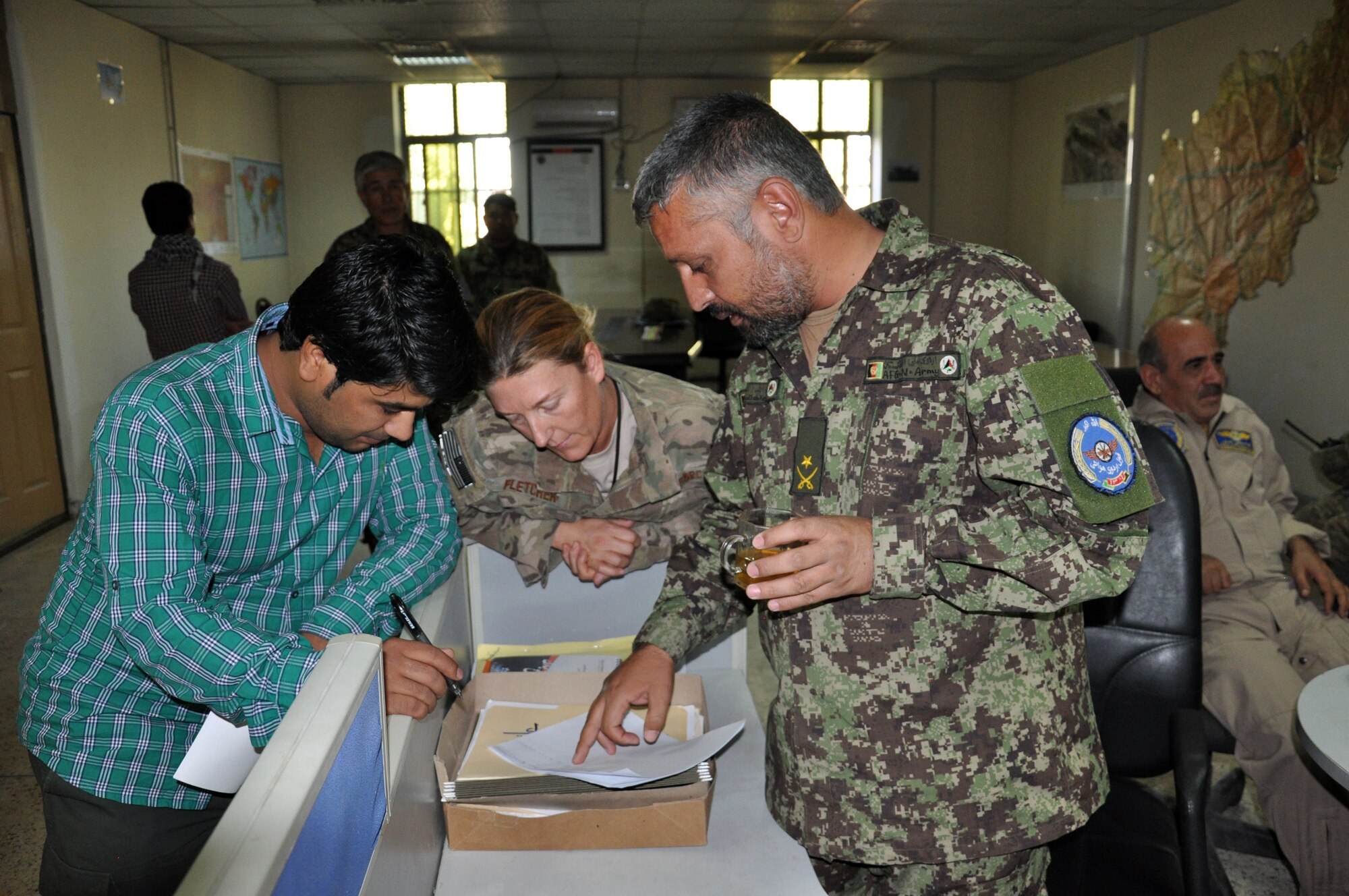 Master Sgt. Jennifer Fletcher, Train, Advise, Assist Command-Air (TAAC-Air) WOC superintendent (center) reviews reports at the Kabul wing operations center Sept. 7, 2015.  Fletcher is the lead advisor for the Afghan Air Force WOC and this was the first Afghan-led exercise scenario planned, coordinated and executed between the Kabul WOC and Afghan command and control center. The advisors were on-hand to ensure the AAF were on-track to achieve their goals, which were to test their communication flow between their two agencies and their abilities to task and launch recovery “exercise” aircraft for a “downed” aircraft.  (U.S. Air Force photo by Capt. Eydie Sakura/released)