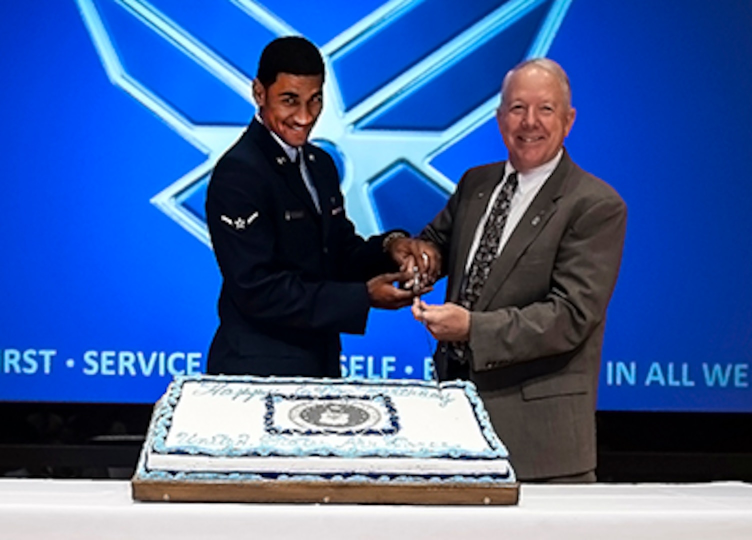 Airman Ivan Velazquez, 88th Air Base Wing, Wright-Patterson Air Force Base, representing the youngest Airman, cuts the cake along with James McClaugherty, Land and Maritime deputy commander and a retired Air Force colonel, at DLA Land and Maritime's Air Force birthday party Sept. 17 in the Building 20 auditorium.