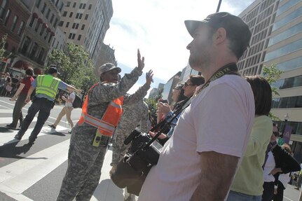 Sgt. Stephanie Wade, 547th Transportation Company, tells the crowd to stay in the designated area while providing traffic control and crowd management during the motorcade, parade and associated activities of the papal visit in Washington, Sept. 23, 2015. The guardsmen aided in peace and order efforts along with accompanying law enforcement agencies.‬
