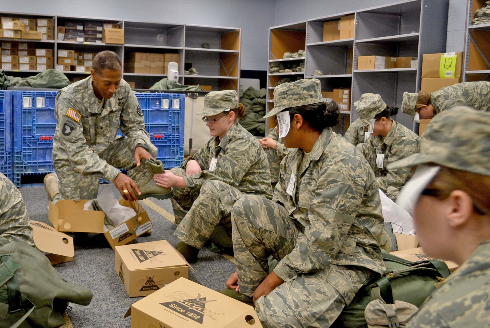 Army Brig. Gen. Charles Hamilton, DLA Troop Support commander, hands a pair of combat boots to an Air Force recruit receiving her initial clothing issue Aug. 6 at Lackland Air Force Base. Hamilton saw technology implemented by the Clothing and Textiles supply chain that helped cut the clothing issue time in half.