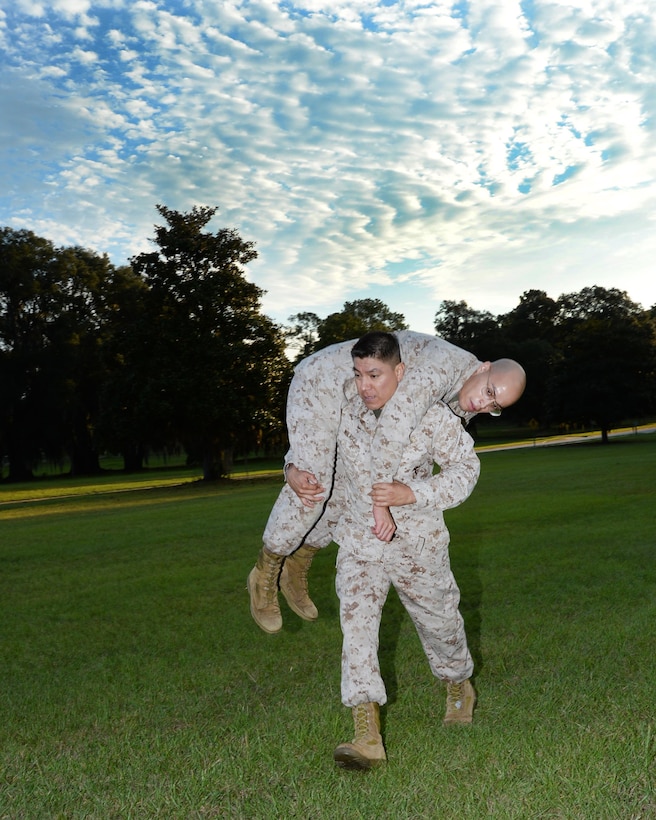 Master Sgt. Roberto Nolasco, operations and training Chief, Marine Corps Logistics Base Albany, carries Cpl. Gregory Perez, administrative specialist, Military Personnel, MCLB Albany, through the maneuver-under-fire portion of the Marine Corps Combat Fitness Test, here, Sept. 22.
