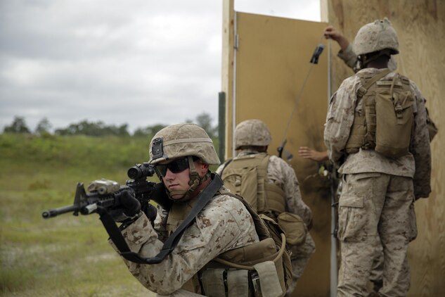 A Marine with 2nd Battalion, 2nd Marine Regiment provides security as Marines in his platoon set up an urban charge on a door during a demolitions exercise with 2nd Combat Engineer Battalion at Engineer Training Area 7 on Camp Lejeune, N.C., Sept. 22, 2015.  Marines with 2/2 increased their proficiency and knowledge with various charges and techniques with the help of 2nd CEB.  (U. S. Marine Corps photo by Cpl. Alexander Mitchell/released)