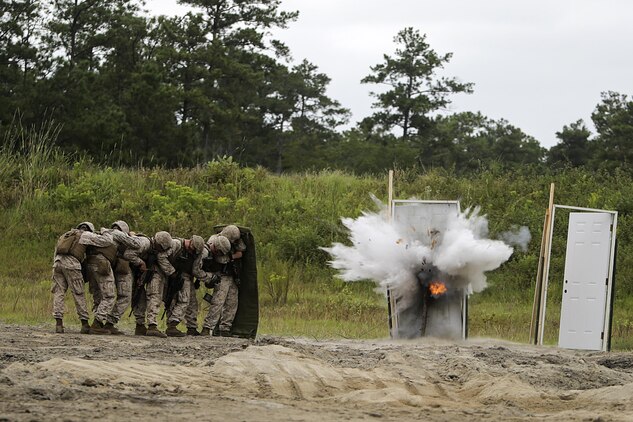 Marines with 2nd Battalion, 2nd Marine Regiment take cover behind a shielding blanket as a water charge detonates during a demolitions exercise with 2nd Combat Engineer Battalion at Engineer Training Area  7 on Camp Lejeune, N.C., Sept. 22, 2015.  Marines with 2/2 increased their proficiency and knowledge with various charges and techniques with the help of 2nd CEB.  (U. S. Marine Corps photo by Cpl. Alexander Mitchell/released)