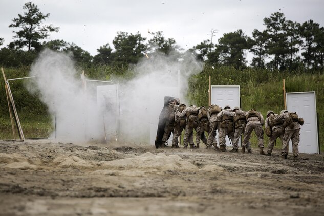 Marines with 2nd Battalion, 2nd Marine Regiment stand behind a shielding blanket as a water charge detonates during a demolitions exercise with 2nd Combat Engineer Battalion at Engineer Training Area  7 on Camp Lejeune, N.C., Sept. 22, 2015.  Marines with 2/2 increased their proficiency and knowledge with various charges and techniques with the help of 2nd CEB.  (U. S. Marine Corps photo by Cpl. Alexander Mitchell/released)