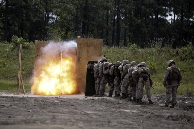 Marines with 2nd Battalion, 2nd Marine Regiment take cover behind a shielding blanket as an urban charge detonates during a demolitions exercise with 2nd Combat Engineer Battalion at Engineer Training Area  7 on Camp Lejeune, N.C., Sept. 22, 2015.  Marines with 2/2 increased their proficiency and knowledge with various charges and techniques with the help of 2nd CEB.  (U. S. Marine Corps photo by Cpl. Alexander Mitchell/released)