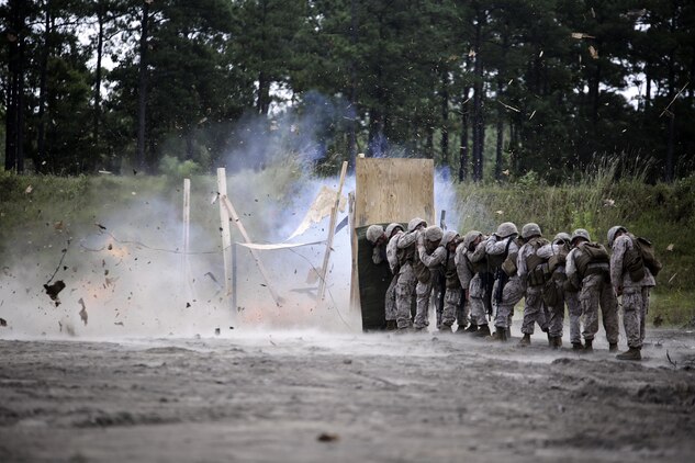 Marines with 2nd Battalion, 2nd Marine Regiment take cover behind a shielding blanket as an urban charge detonates during a demolitions exercise with 2nd Combat Engineer Battalion at Engineer Training Area  7 on Camp Lejeune, N.C., Sept. 22, 2015.  Marines with 2/2 increased their proficiency and knowledge with various charges and techniques with the help of 2nd CEB.  (U. S. Marine Corps photo by Cpl. Alexander Mitchell/released)