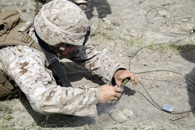 A Marine with 2nd Battalion, 2nd Marine Regiment lays in the prone while he pulls the timed fuse on a bangalore charge to destroy a wire trap during a demolitions exercise with 2nd Combat Engineer Battalion at Engineer Training Area  7 on Camp Lejeune, N.C., Sept. 22, 2015.  Marines with 2/2 increased their proficiency and knowledge with various charges and techniques with the help of 2nd CEB.  (U. S. Marine Corps photo by Cpl. Alexander Mitchell/released)