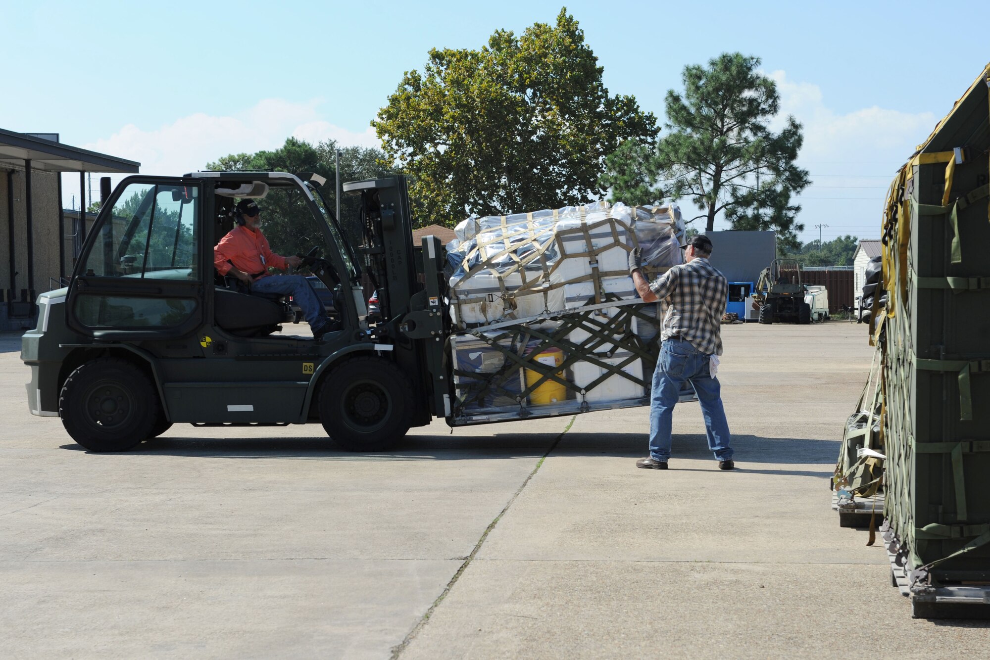 Reid Cuevas, 81st Logistics Readiness Squadron forklift operator, provides direction to Marc Lerch, 81st LRS packing and crating technician, as he operates a forklift to transport cargo at the supply warehouse loading docks during a deployment exercise Sept. 23, 2015, Keesler Air Force Base, Miss. The exercise scenario tested the mission readiness of Team Keesler members for world-wide deployments. (U.S. Air Force photo by Kemberly Groue)