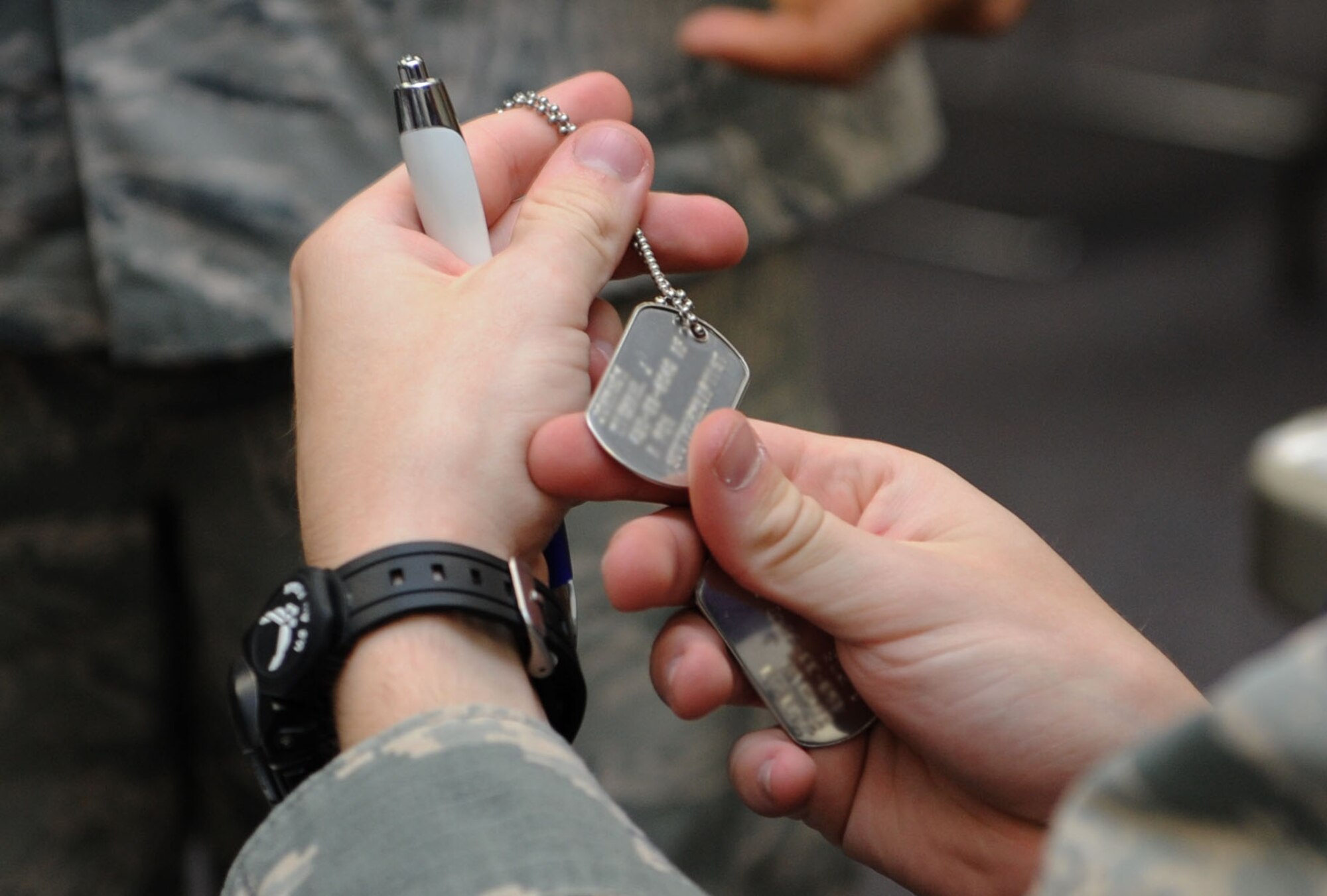 Airman 1st Class Cory Easley, 81st Force Support Squadron customer support technician, inspects a set of dog tags as Airmen process through the deployment eligibility line during a deployment exercise at the Taylor Logistics Center Sept. 24, 2015, Keesler Air Force Base, Miss. The exercise scenario tested the mission readiness of Team Keesler members for world-wide deployments. (U.S. Air Force photo by Kemberly Groue)