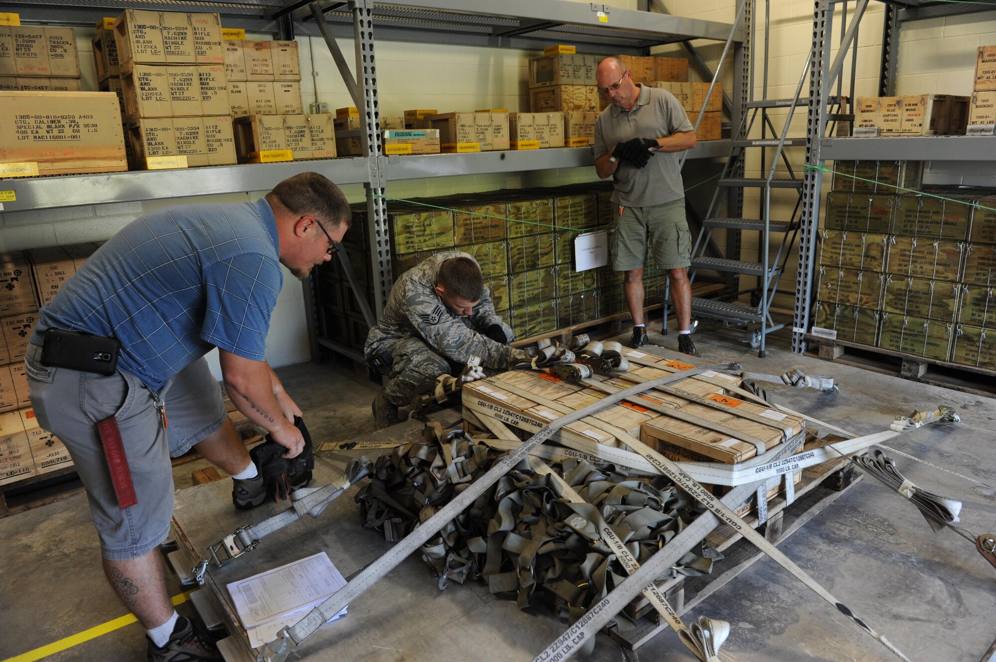 Staff Sgt. David Frahm, 81st Logistics Readiness Squadron deployment joint inspector, (center), inspects a base personnel ammunitions pallet with the assistance of Joe Taylor and Lawerance Yoho, Base Operations Support munitions storage technicians, during a deployment exercise Sept. 23, 2015, Keesler Air Force Base, Miss. The exercise scenario tested the mission readiness of Team Keesler members for world-wide deployments. (U.S. Air Force photo by Kemberly Groue)