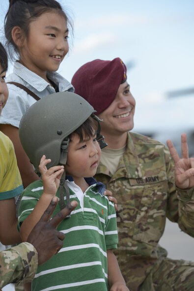 Japanese children take a photo with US Army Staff Sgt. Brian Wright during the 2015 Japanese-American Friendship Festival at Yokota Air Base, Japan, Sept. 20, 2015. Wright is with the 1st Battalion, 1st Special Operations Group (Airborne), whose members jumped from C-130 Hercules during the festival to highlight the airdrop capability at Yokota. After the jump, the Soldiers greeted festival attendees. (U.S. Air Force photo by Staff Sgt. Cody H. Ramirez/Released) 