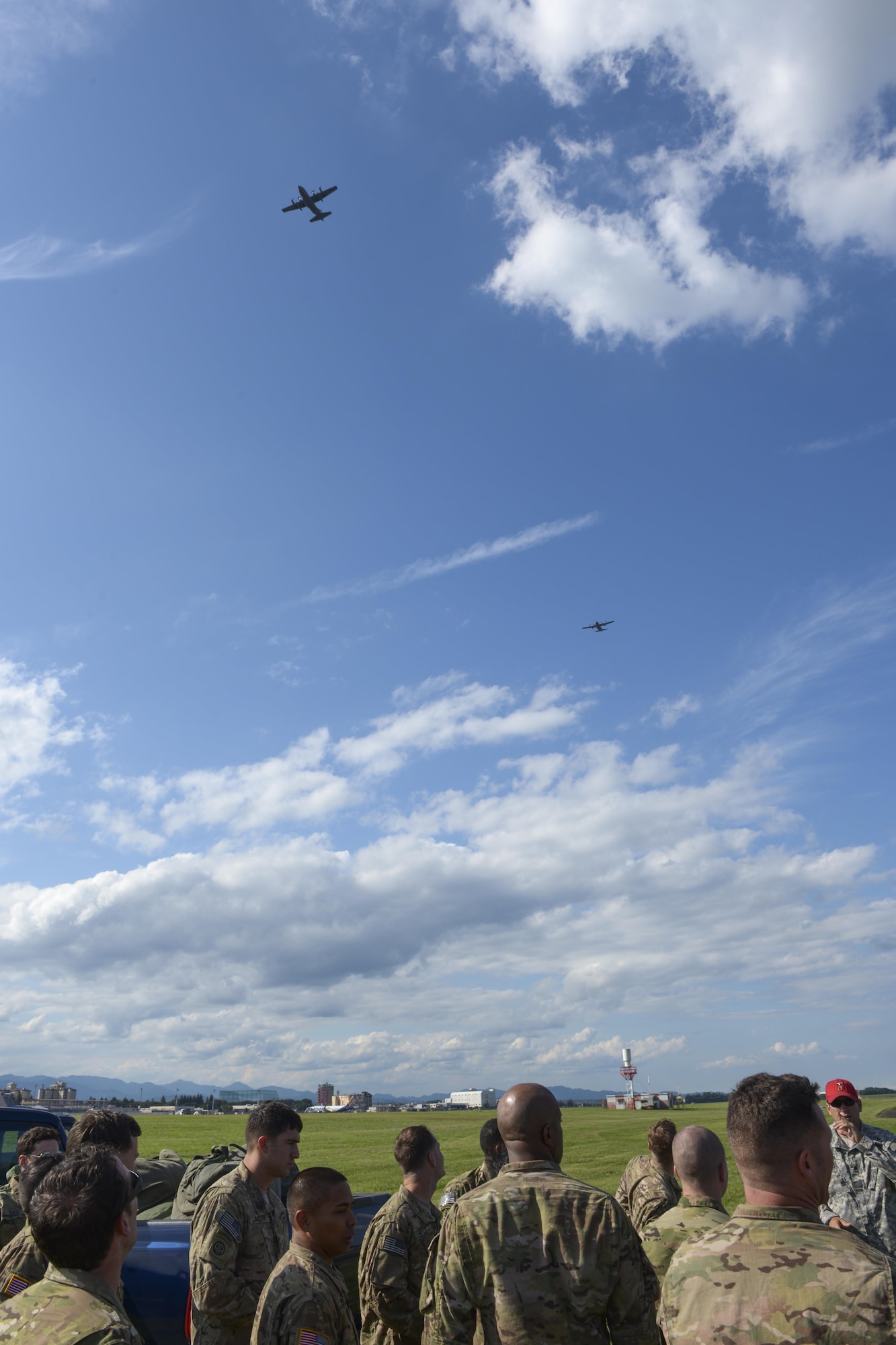 Two C-130 Hercules with the 36th Airlift Squadron fly above Soldiers with the 1st Battalion, 1st Special Operations Group (Airborne), after conducting a personnel air drop during the 2015 Japanese-American Friendship Festival at Yokota Air Base, Japan, Sept. 19, 2015. The jump displayed Yokota's airdrop capability to the festival attendees while also allowing the Airborne members to receive scheduled training and update jump currency. (U.S. Air Force photo by Staff Sgt. Cody H. Ramirez/Released)