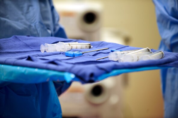 A nurse carries a tray of biopsy needles and syringes to an operating table during a bone marrow collection procedure at Banner-University Medical Center in Tucson, Ariz., July 2015. The needles are placed in the left and right sides of a donor's lower back and are used to extract 1-2 liters of rich marrow from the hips. (U.S. Air Force photo by Airman 1st Class Chris Drzazgowski/Released) 